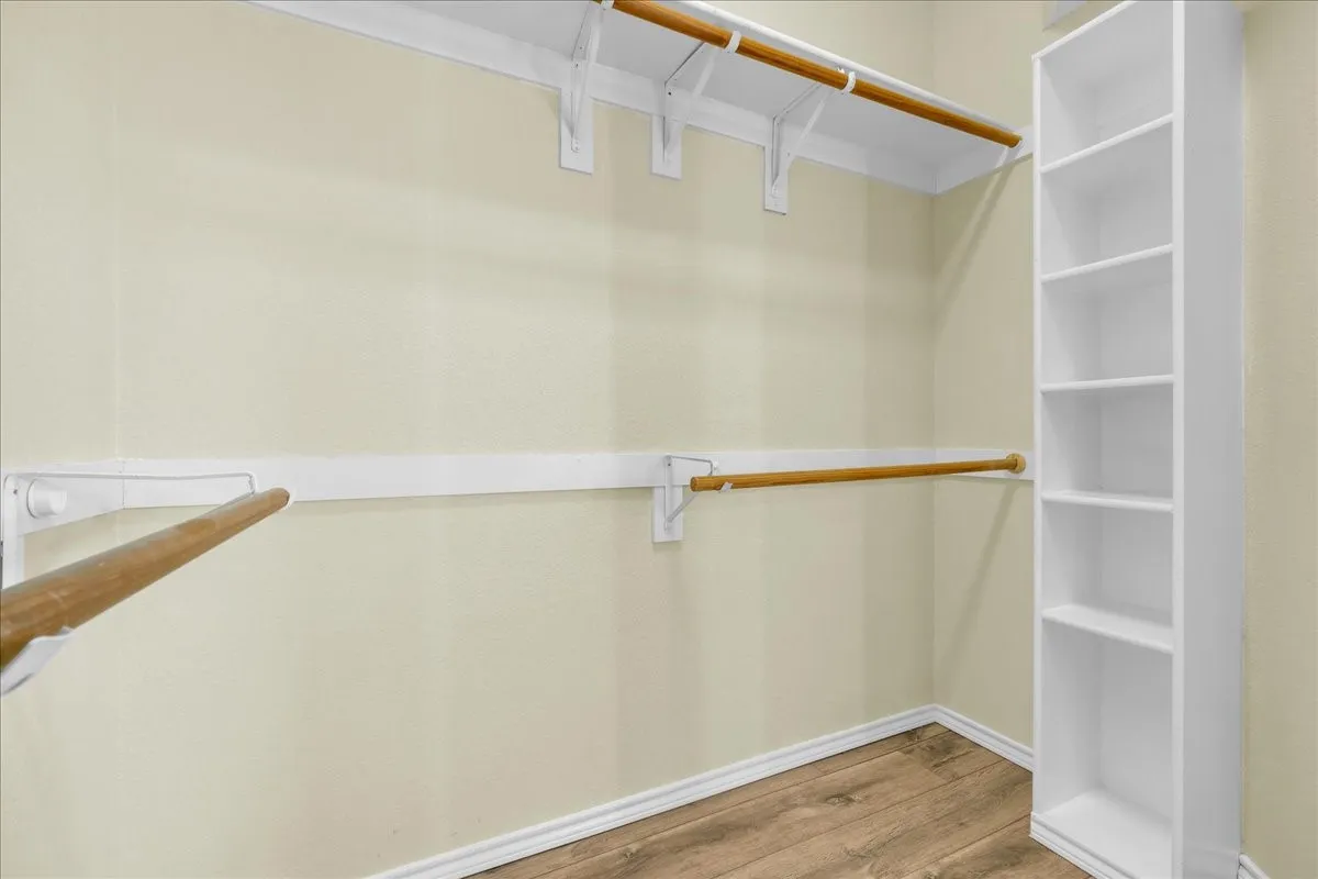 Wood-finish flooring, built-in shelving, and two wooden hanging rods with white brackets