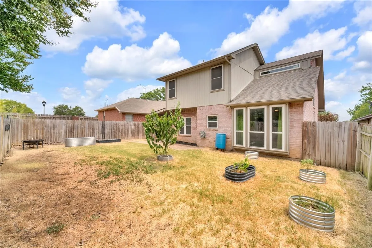 Expansive backyard with a full privacy fence, raised garden beds, and a brick and siding exterior