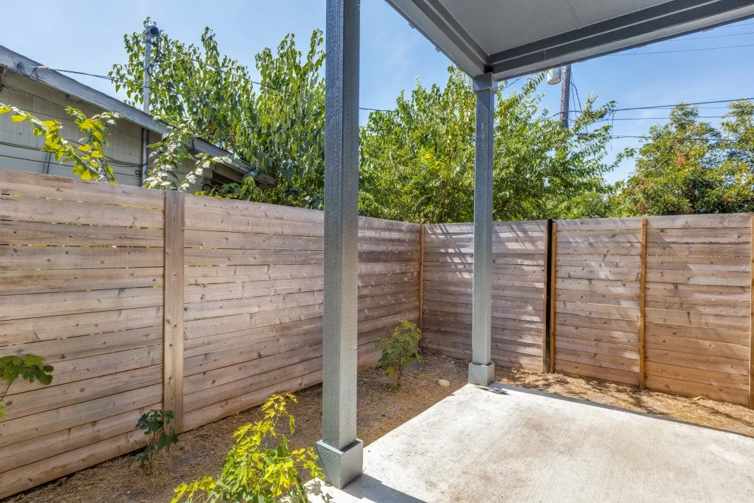Covered concrete patio with a wood privacy fence