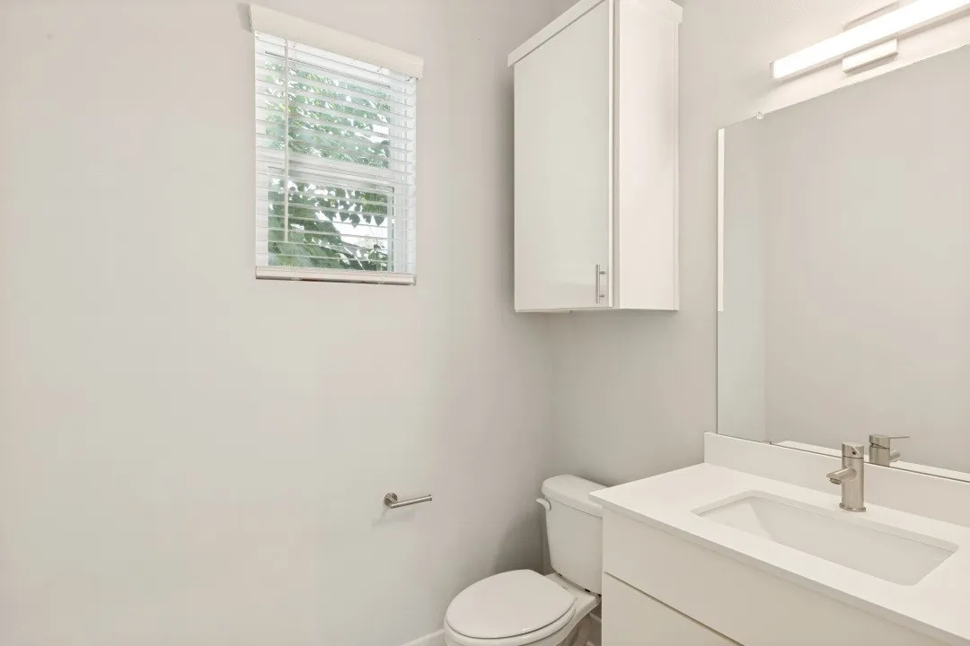White vanity with a rectangular undermount sink and brushed nickel faucet
