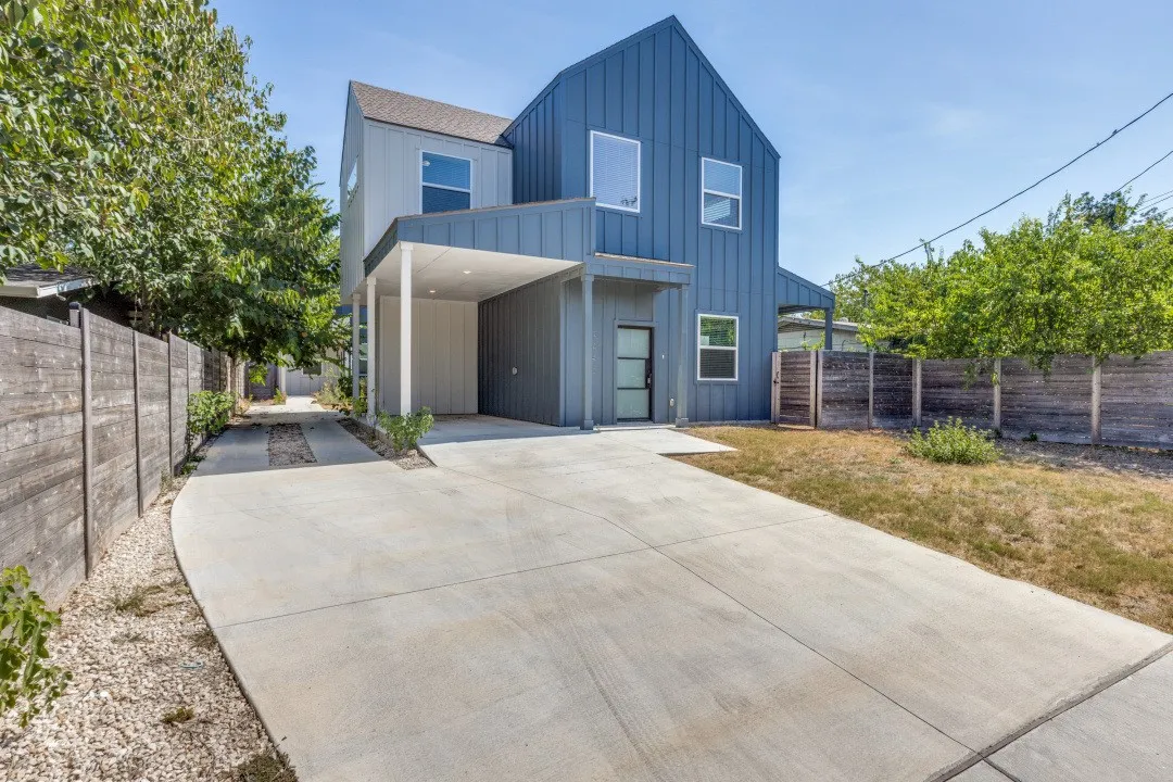 Modern architectural design featuring vertical siding, a covered entryway, and a concrete driveway