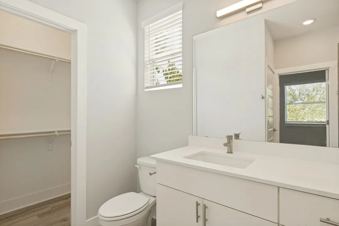 White vanity with integrated rectangular sink, single-handle faucet, and overhead bar light
