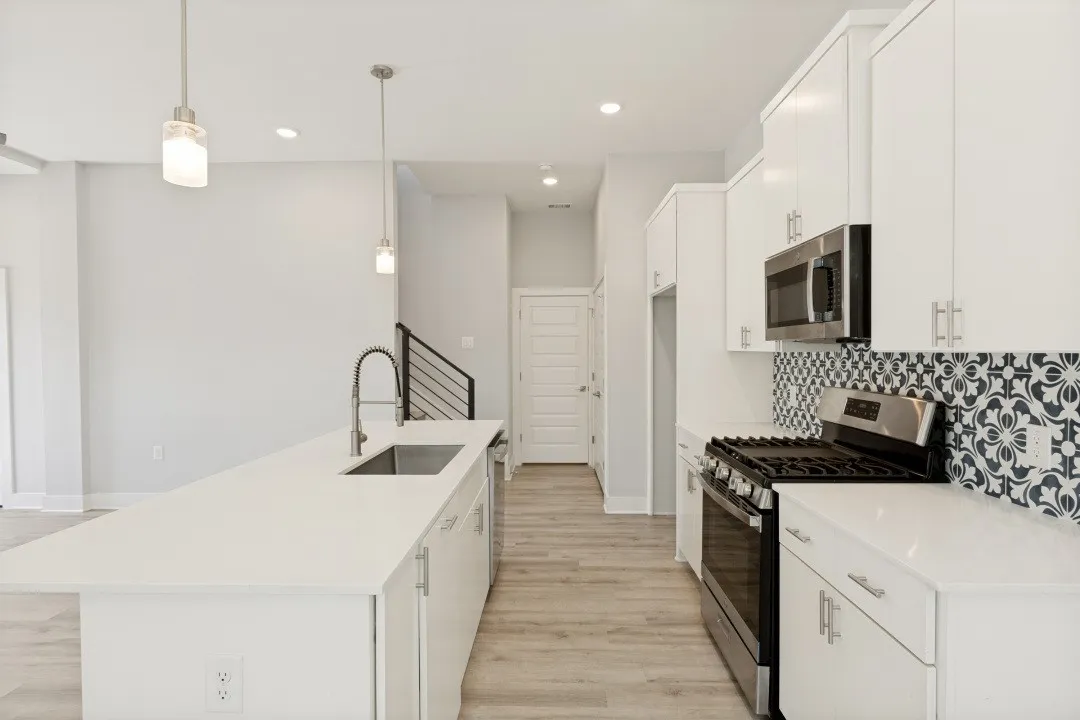 Bright kitchen featuring a center island, stainless steel appliances, white cabinetry, and a patterned tile backsplash