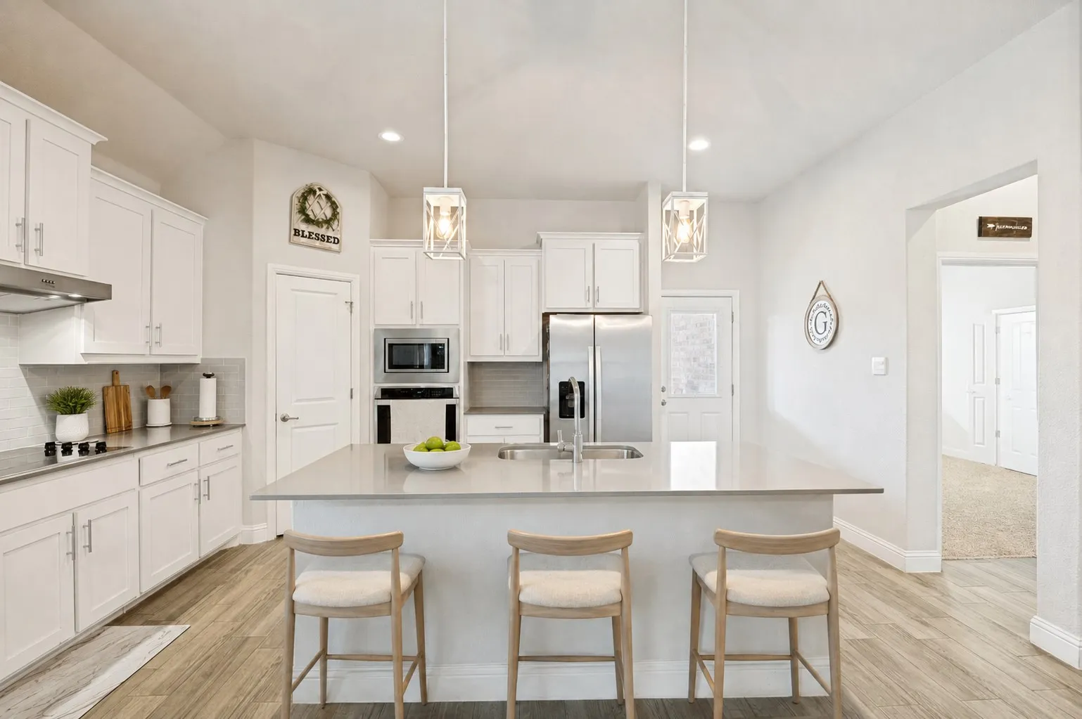 **Virtually staged for effect**Kitchen featuring a central island with countertop seating, white cabinetry, stainless steel appliances, and wood-finish flooring