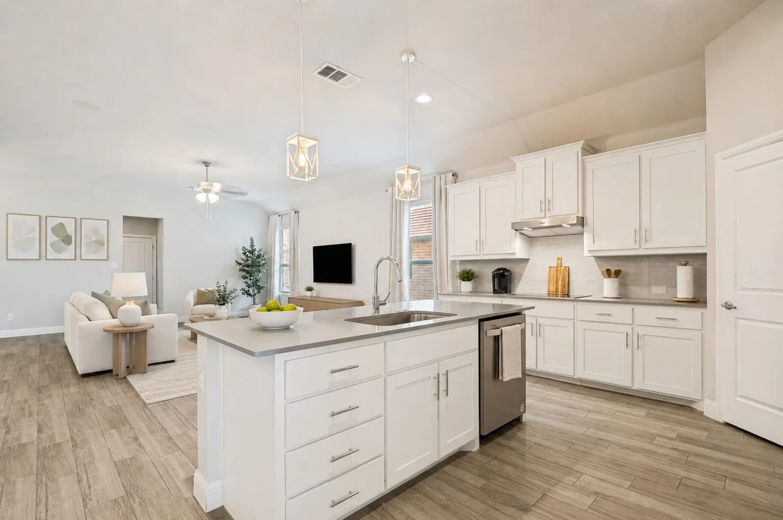 **Virtually staged for effect**Open-concept kitchen featuring an island with an undermount sink, white cabinetry, stainless steel appliances, and wood-finish flooring