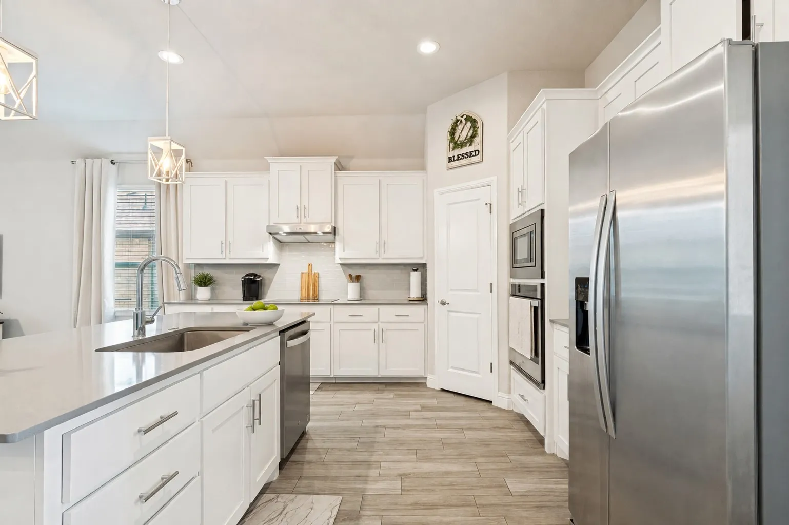 **Virtually staged for effect**Gourmet kitchen with white cabinetry, stainless steel appliances, a center island with sink, quartz countertops, and wood-finish flooring