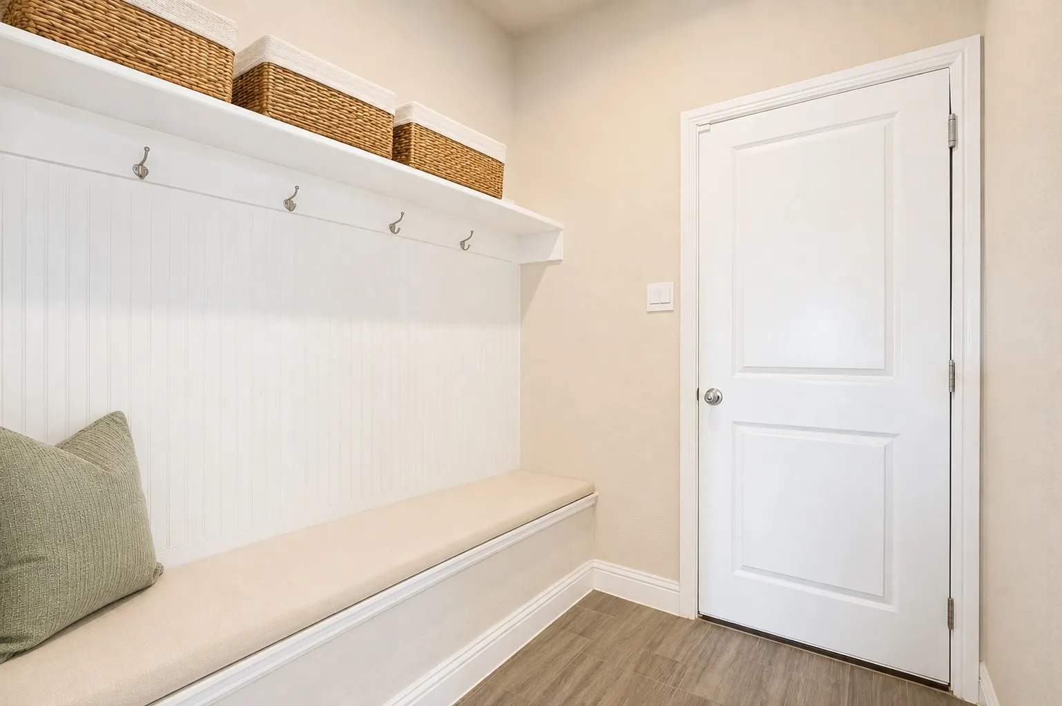 **Virtually staged for effect**Built-in bench with cushioned seating, beadboard paneling, integrated shelving, and wall-mounted hooks
