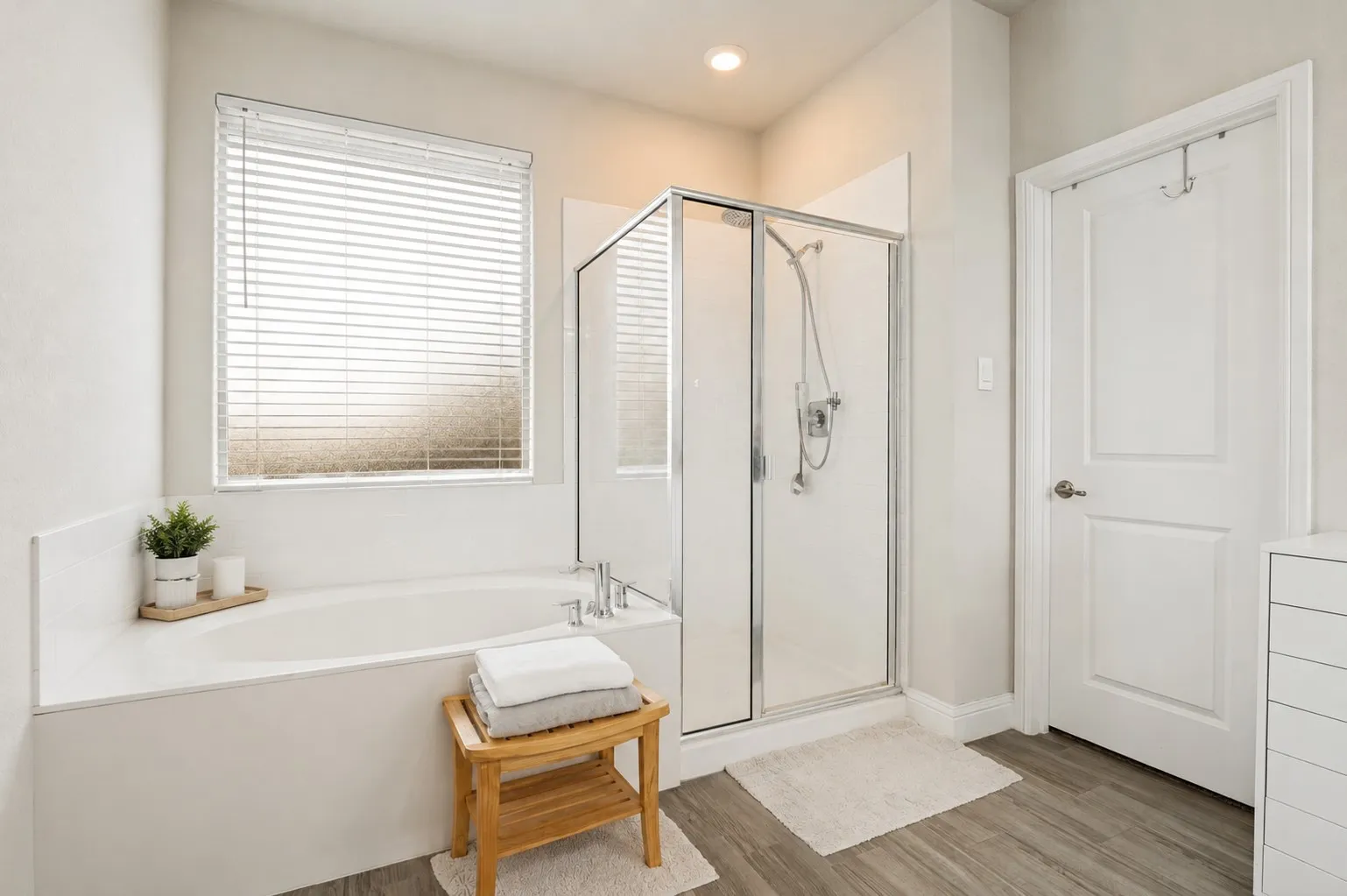 **Virtually staged for effect**Built-in soaking tub, walk-in shower with glass enclosure, wood-finish flooring, recessed lighting, and a window with blinds