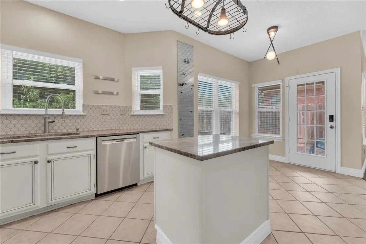 Kitchen featuring white cabinetry, a central island with a stone countertop, stainless steel appliances, and a tiled floor