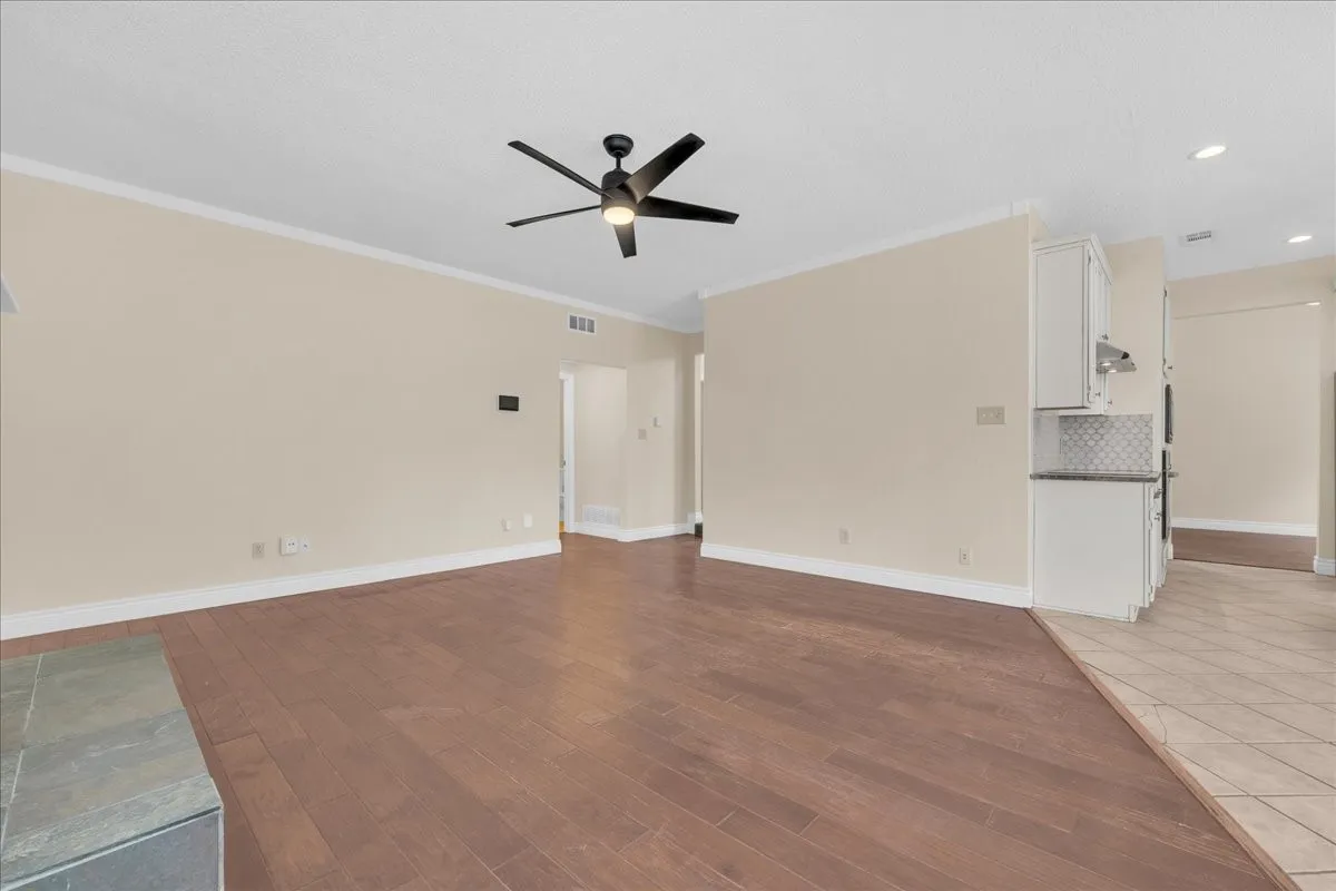 Wood-finish flooring, crown molding, and a modern ceiling fan
