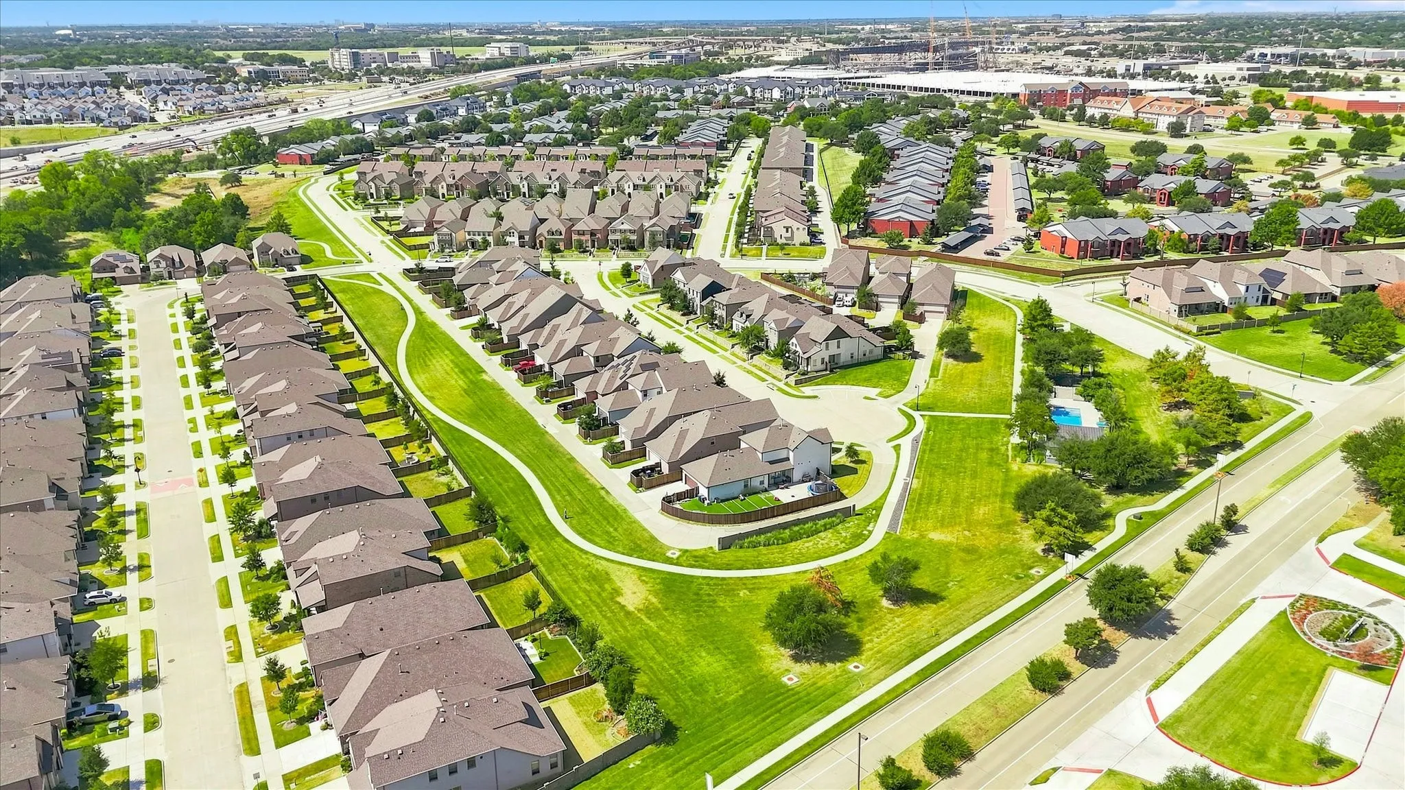 Residential community featuring numerous detached homes, shared green spaces, and a swimming pool