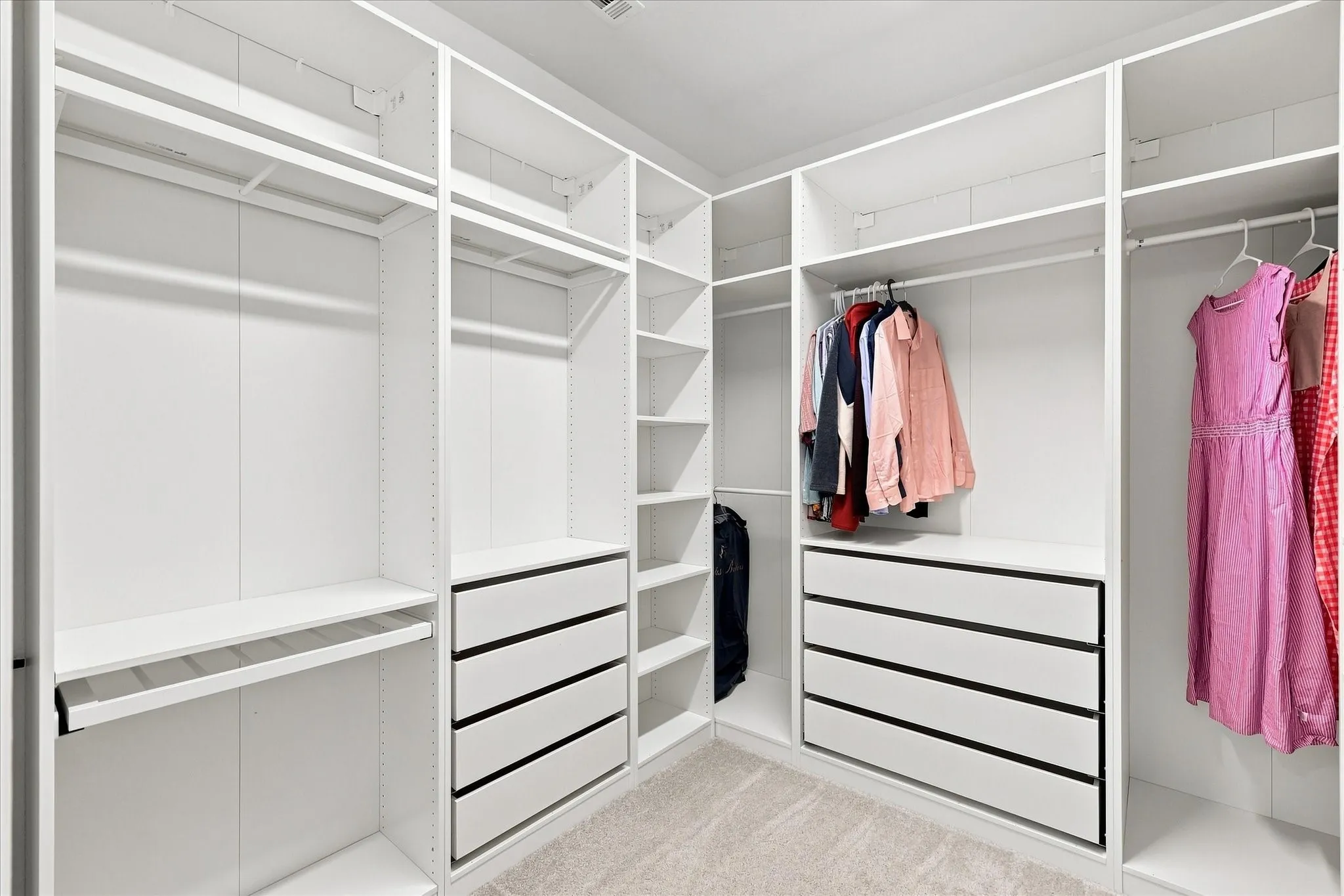 Custom closet system featuring multiple hanging rods, integrated shelving, and built-in drawers with black hardware