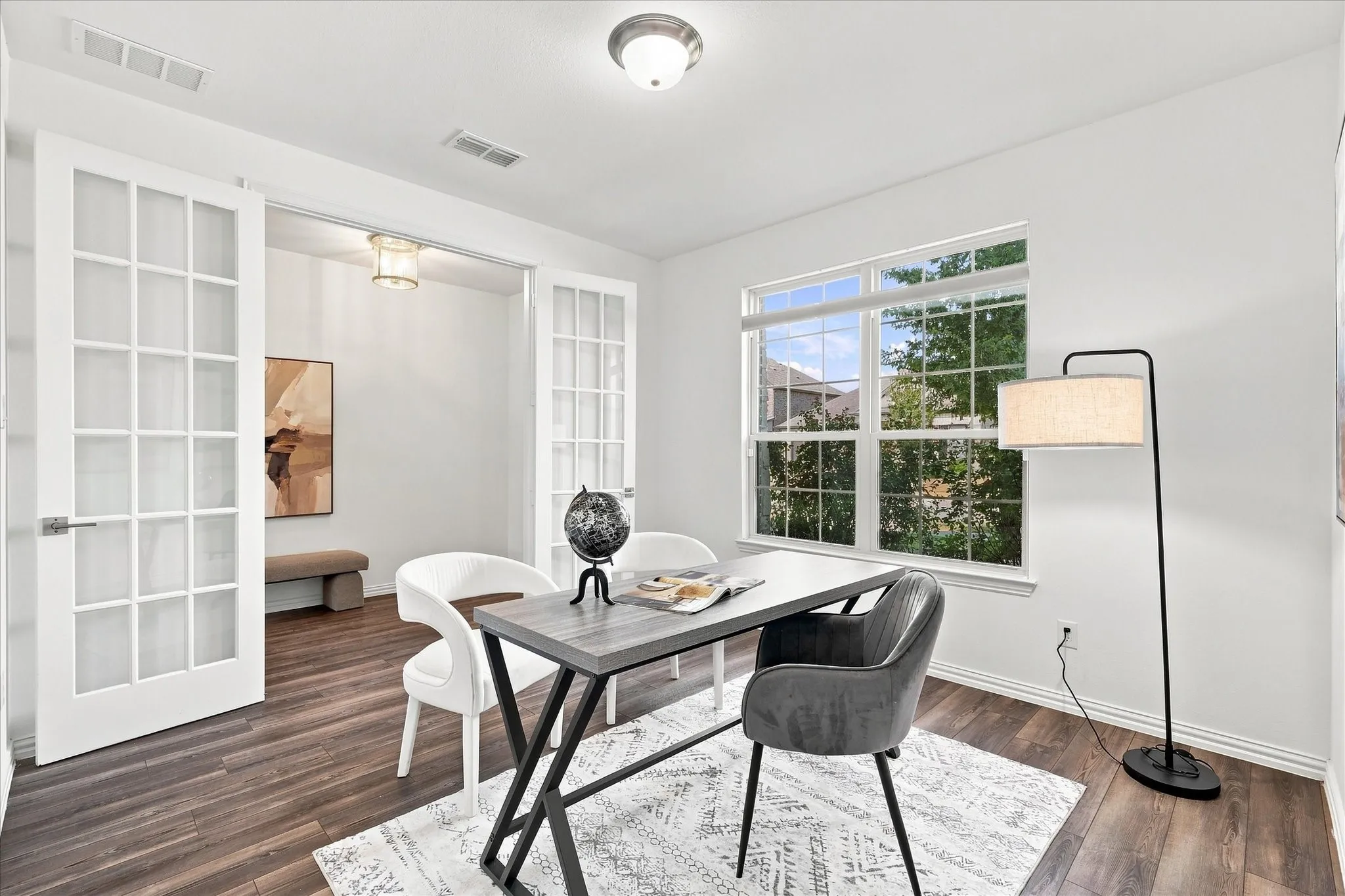 Bright room featuring wood-finish flooring, a large window, and double French doors with frosted panes