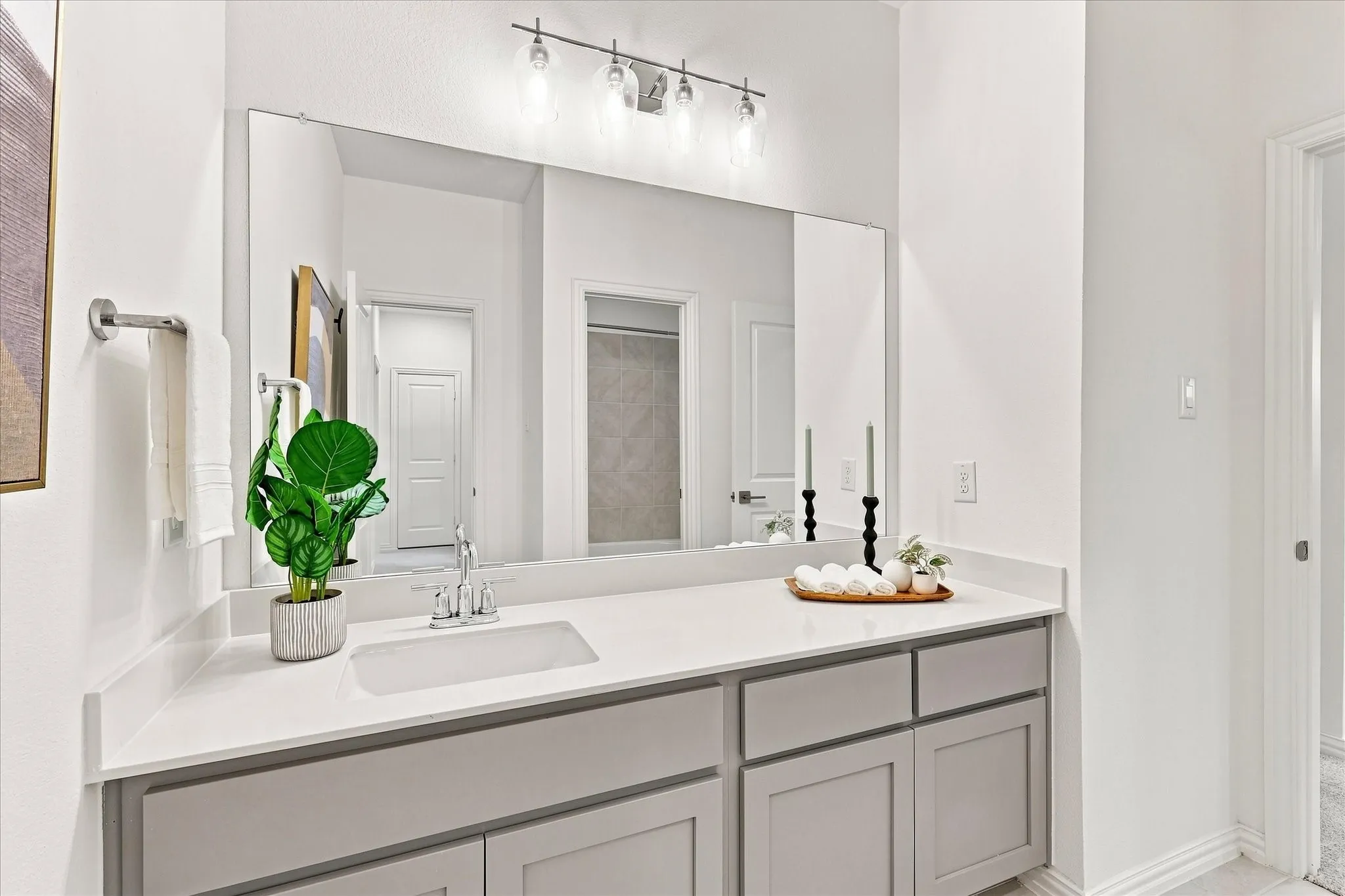 Vanity with light gray shaker cabinetry, a white countertop, an undermount sink, and a large mirror