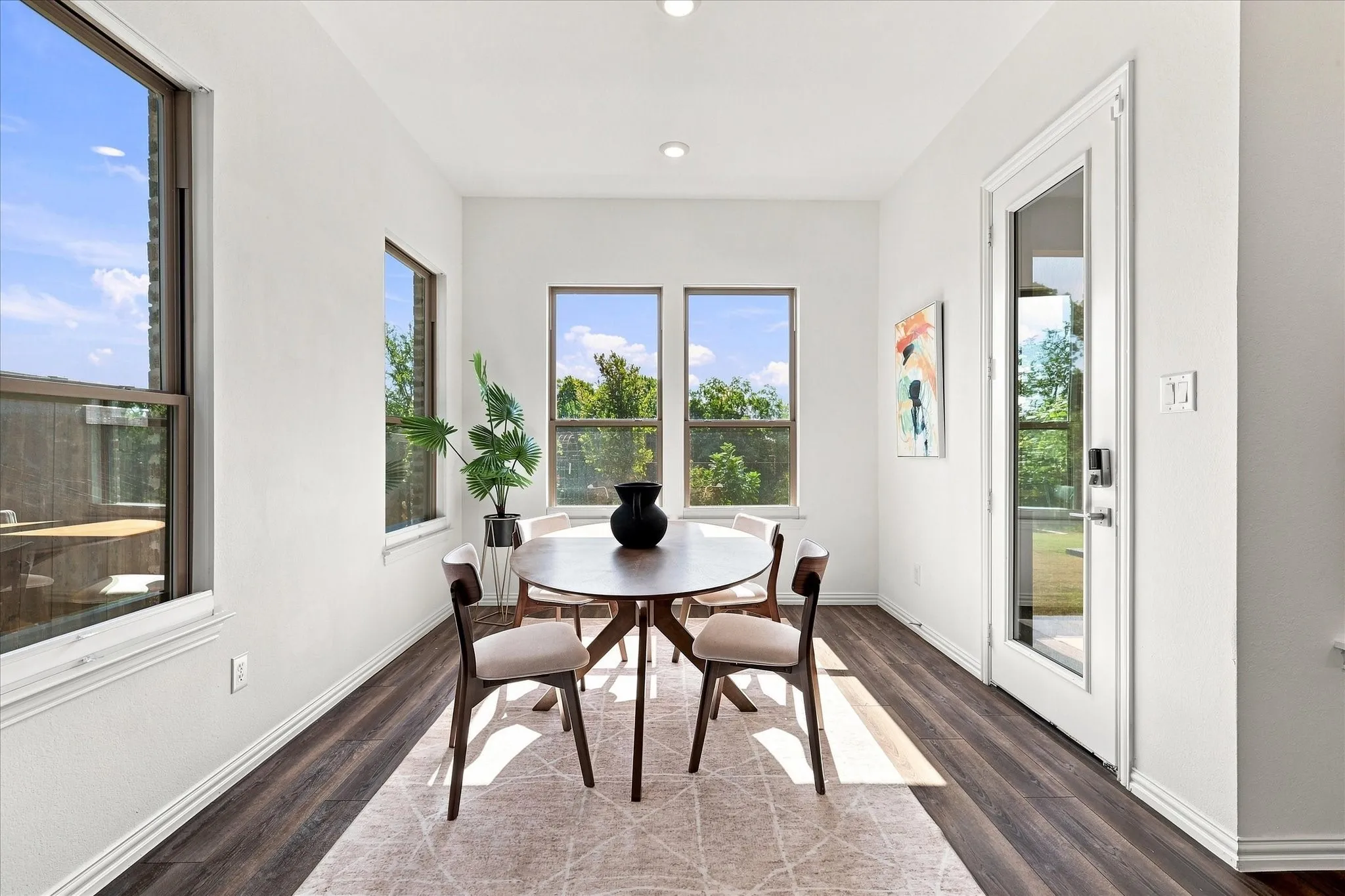 Recessed lighting, wood-finish flooring, multiple windows, and a glass-paneled door