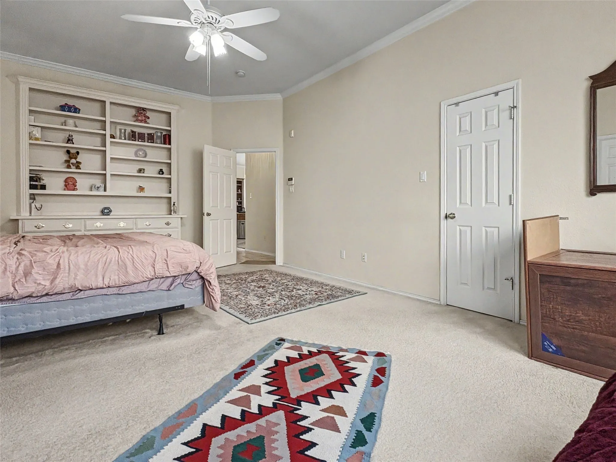 Vaulted ceiling, crown molding, built-in shelving, paneled interior doors, and a ceiling fan with integrated lighting