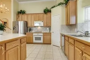 Kitchen featuring wood cabinetry, stainless steel appliances, tile flooring, and a tile backsplash