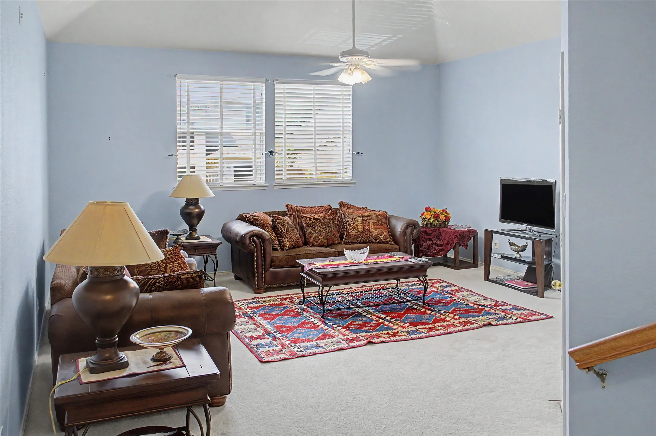 Vaulted ceiling with a ceiling fan, carpeted flooring, and window blinds