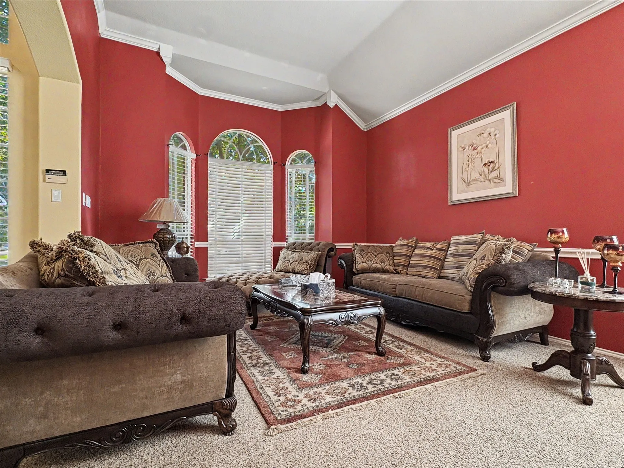 Arched windows with horizontal blinds, vaulted ceiling, and crown molding