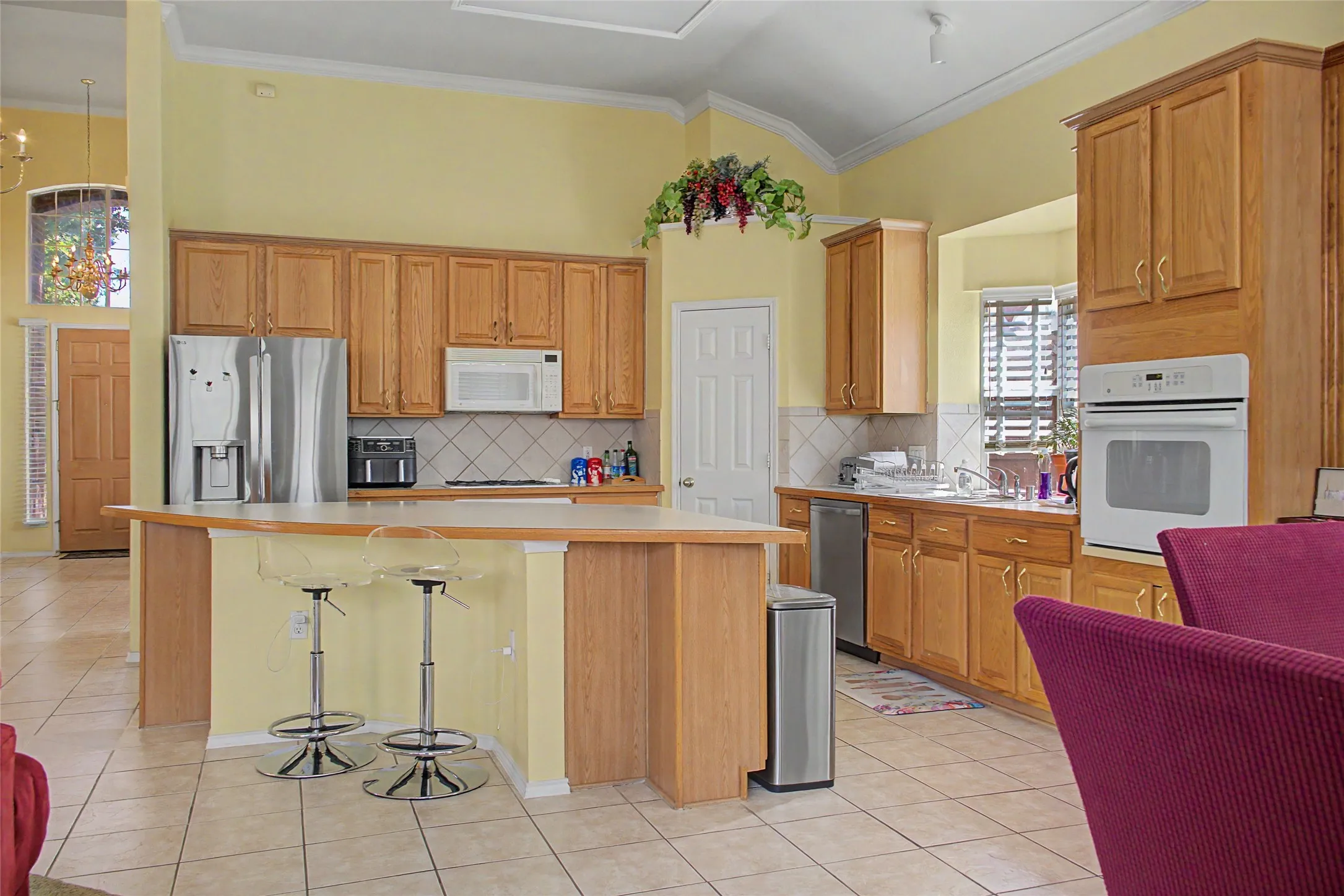 Kitchen featuring wood-finish cabinetry, tile flooring, and integrated white appliances