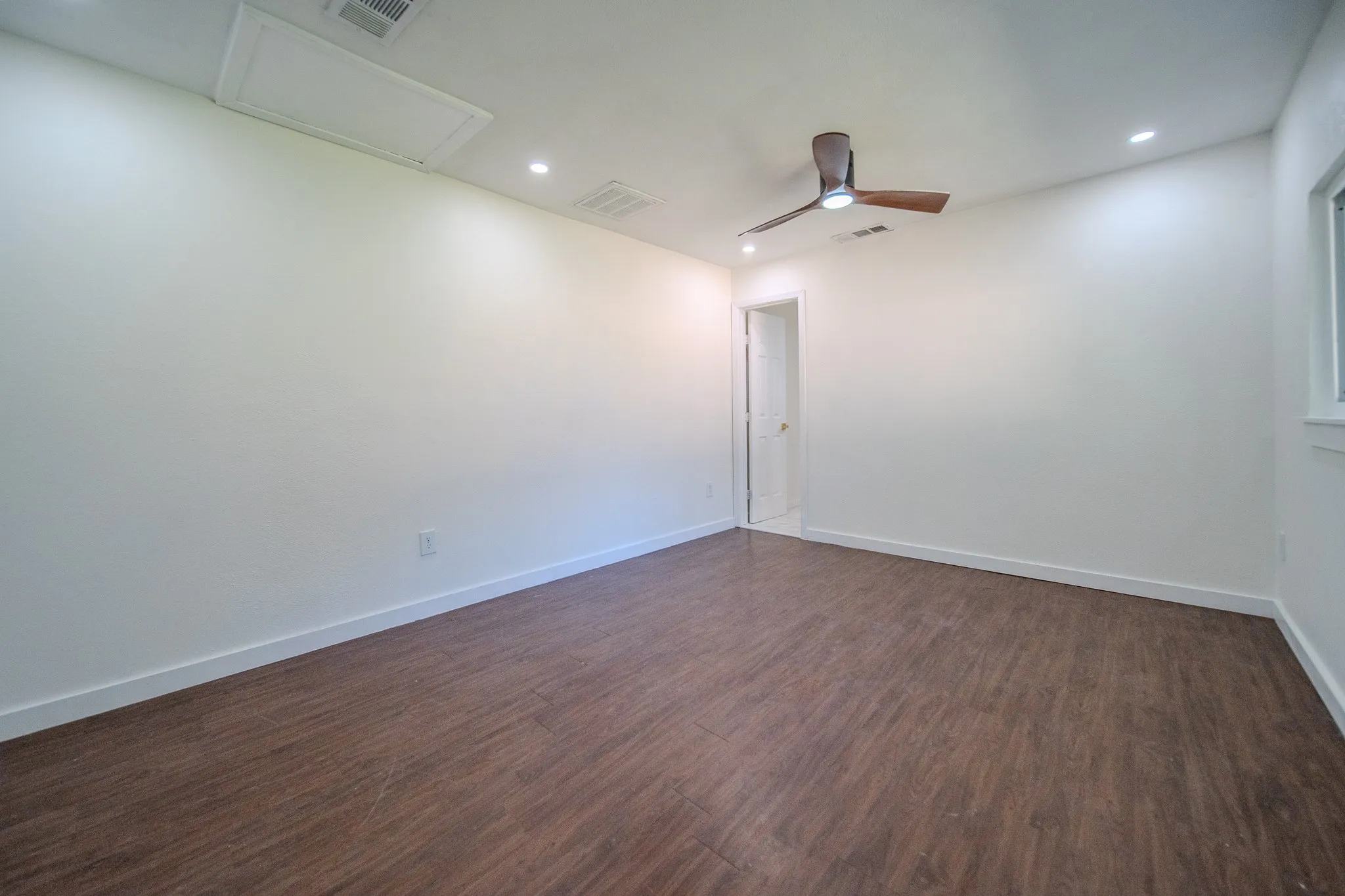 Spacious room featuring wood-finish flooring, recessed lighting, and a ceiling fan