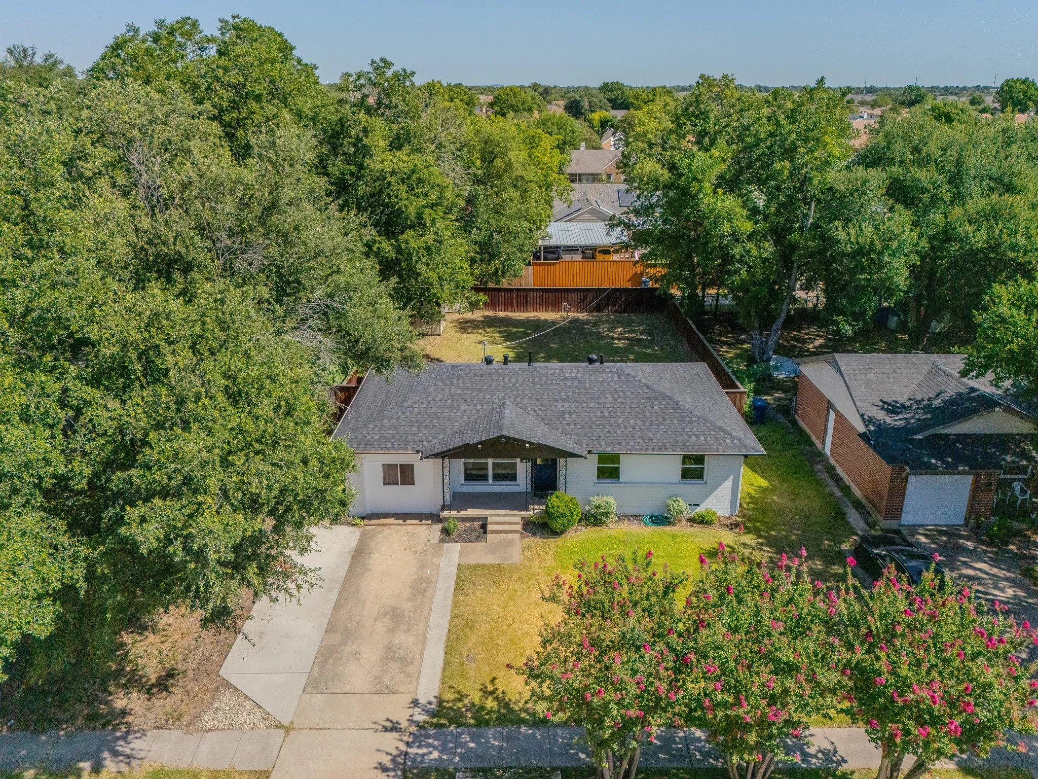 Front exterior with a dark shingle roof, white siding, and a concrete driveway