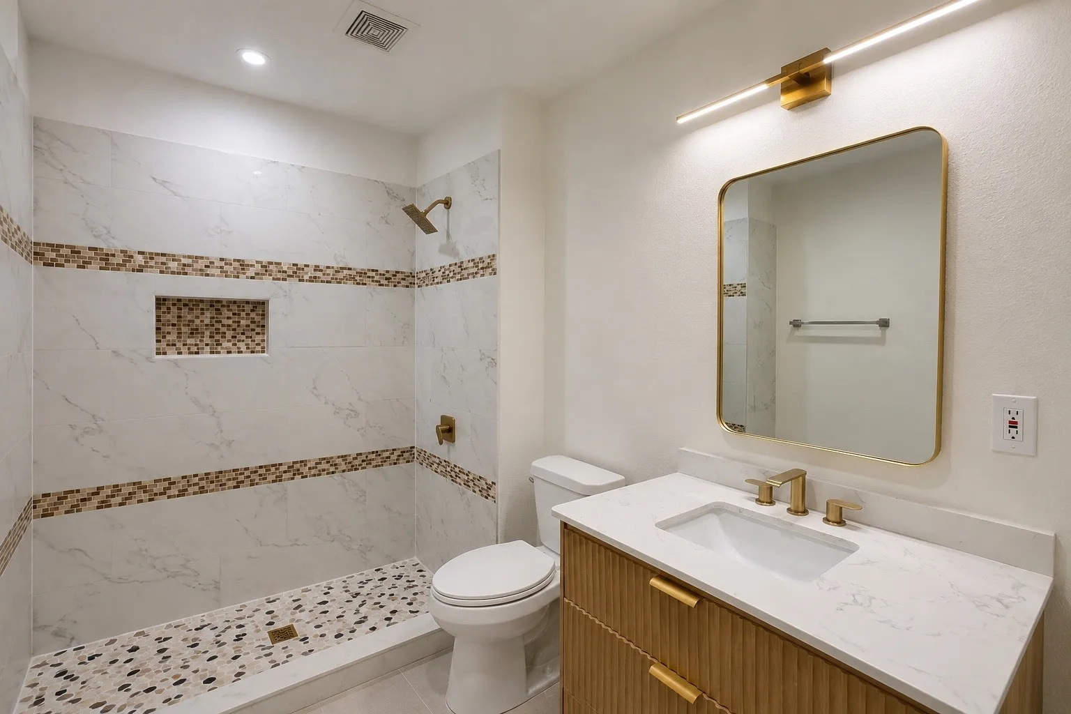 Walk-in shower with pebble tile floor and integrated niche