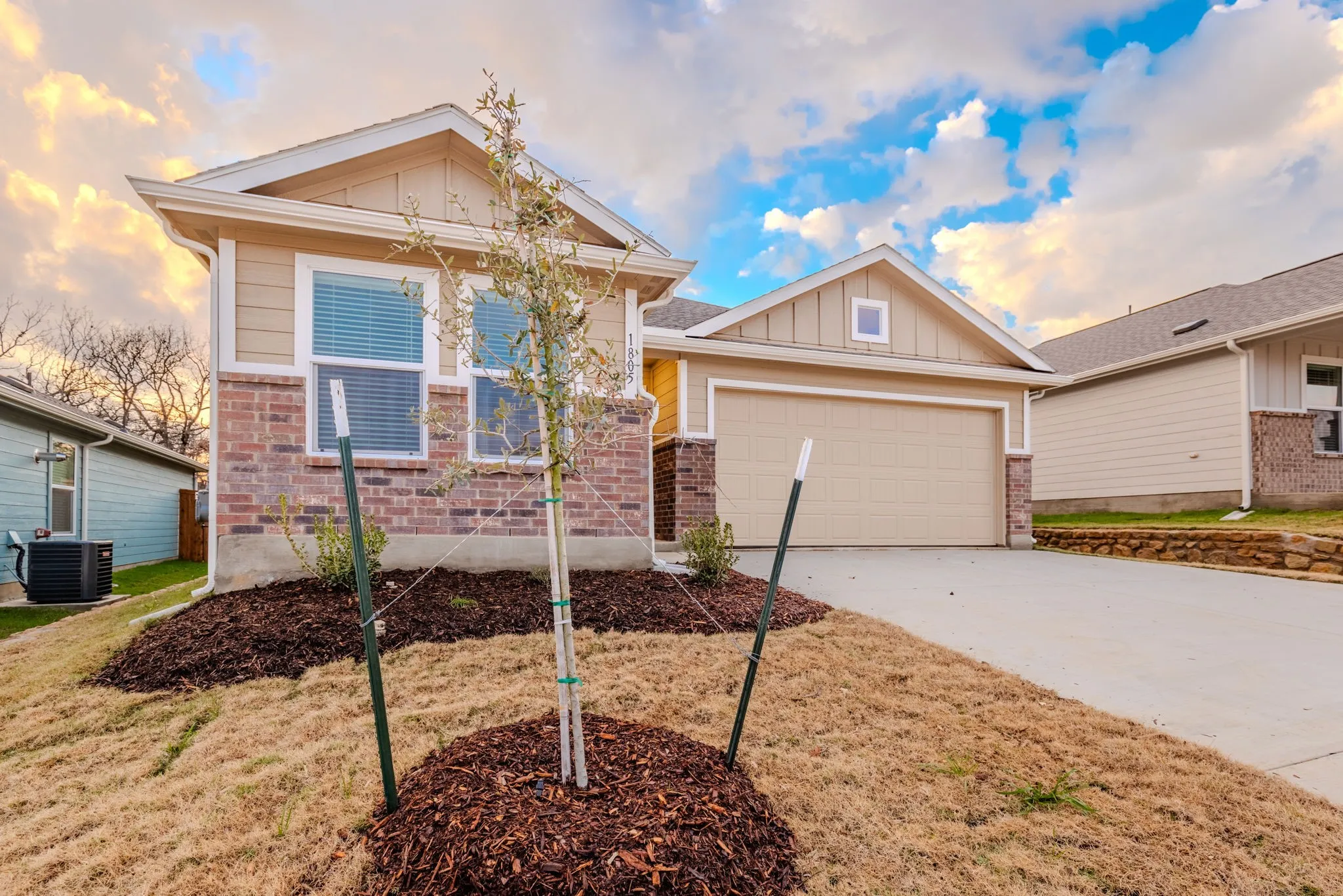 View of front of home featuring a lawn, central AC, and a garage