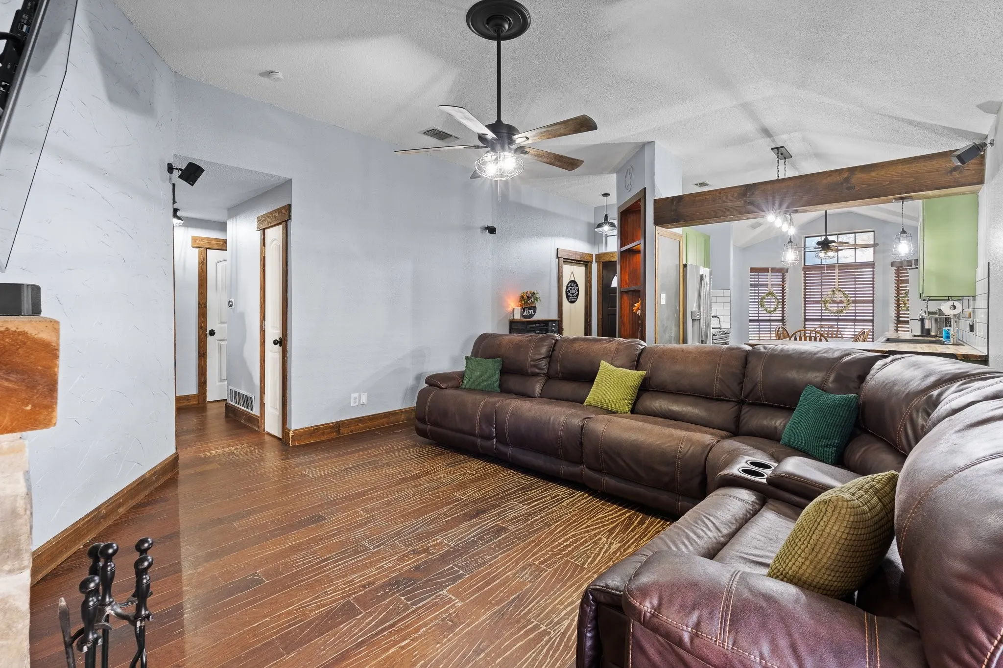 Vaulted ceiling with a ceiling fan, wood-finish flooring, exposed wood beam, recessed lighting, and built-in shelving