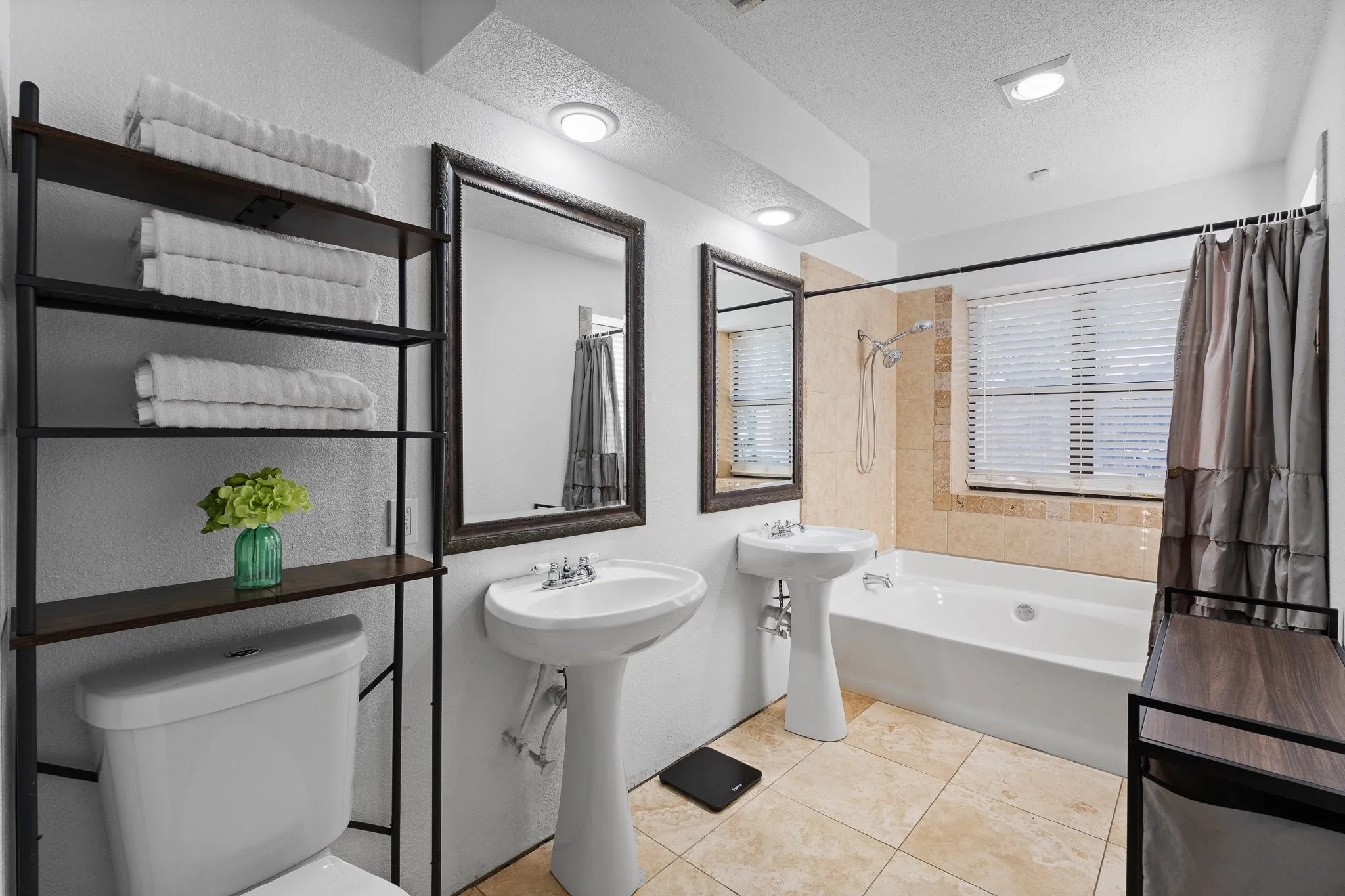 Dual pedestal sinks, tile flooring, built-in bathtub with tile surround, and recessed lighting