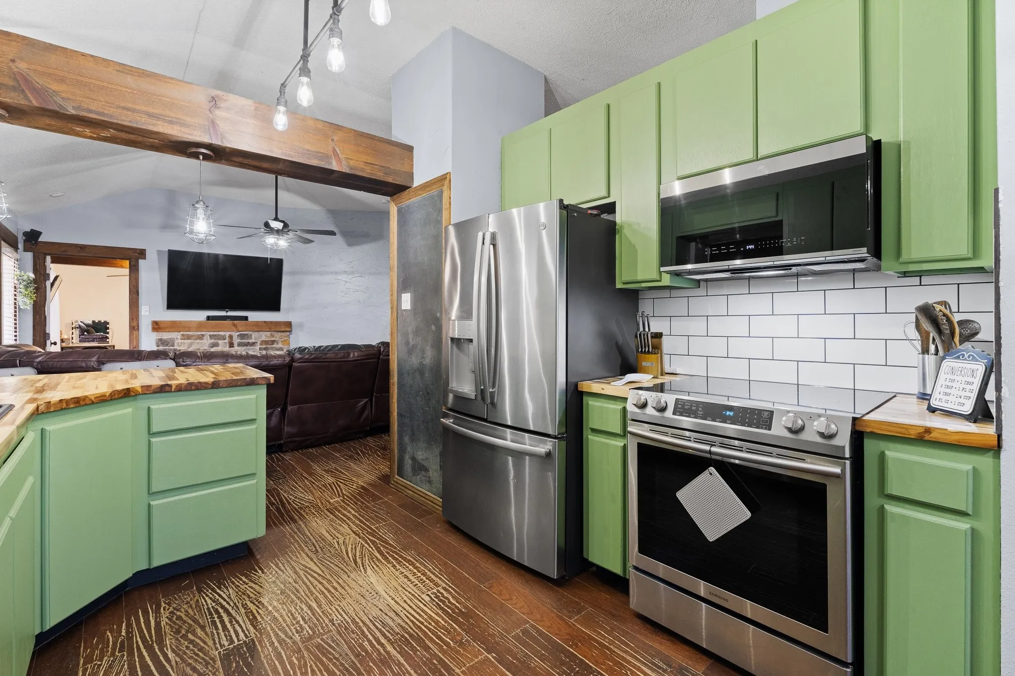 Kitchen featuring green cabinetry, wood-finish countertops, stainless steel appliances, and a subway tile backsplash