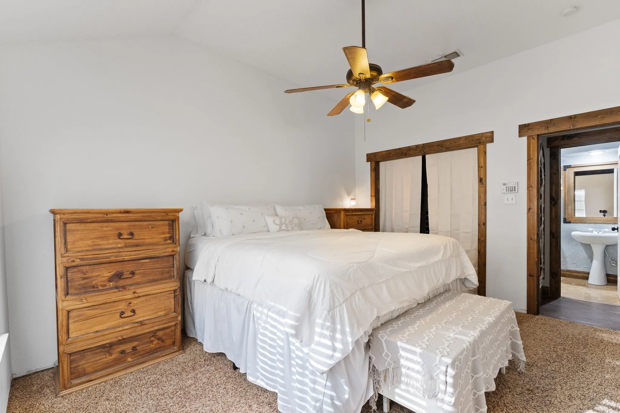 Vaulted ceiling with a ceiling fan, wood-finish door frames, and carpeted flooring
