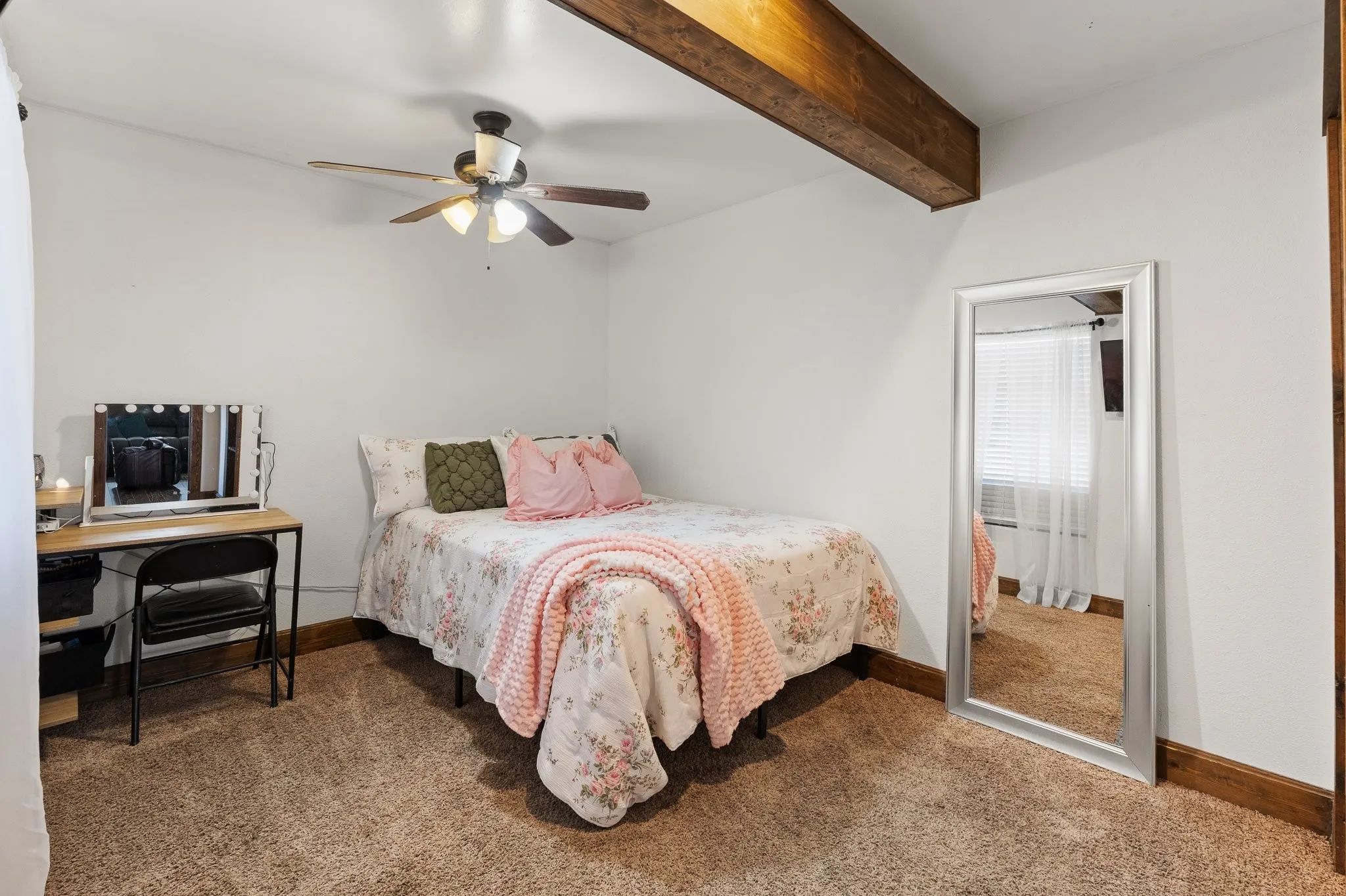 Ceiling fan with integrated lighting, exposed wood ceiling beam, white painted walls, and wood-finish trim
