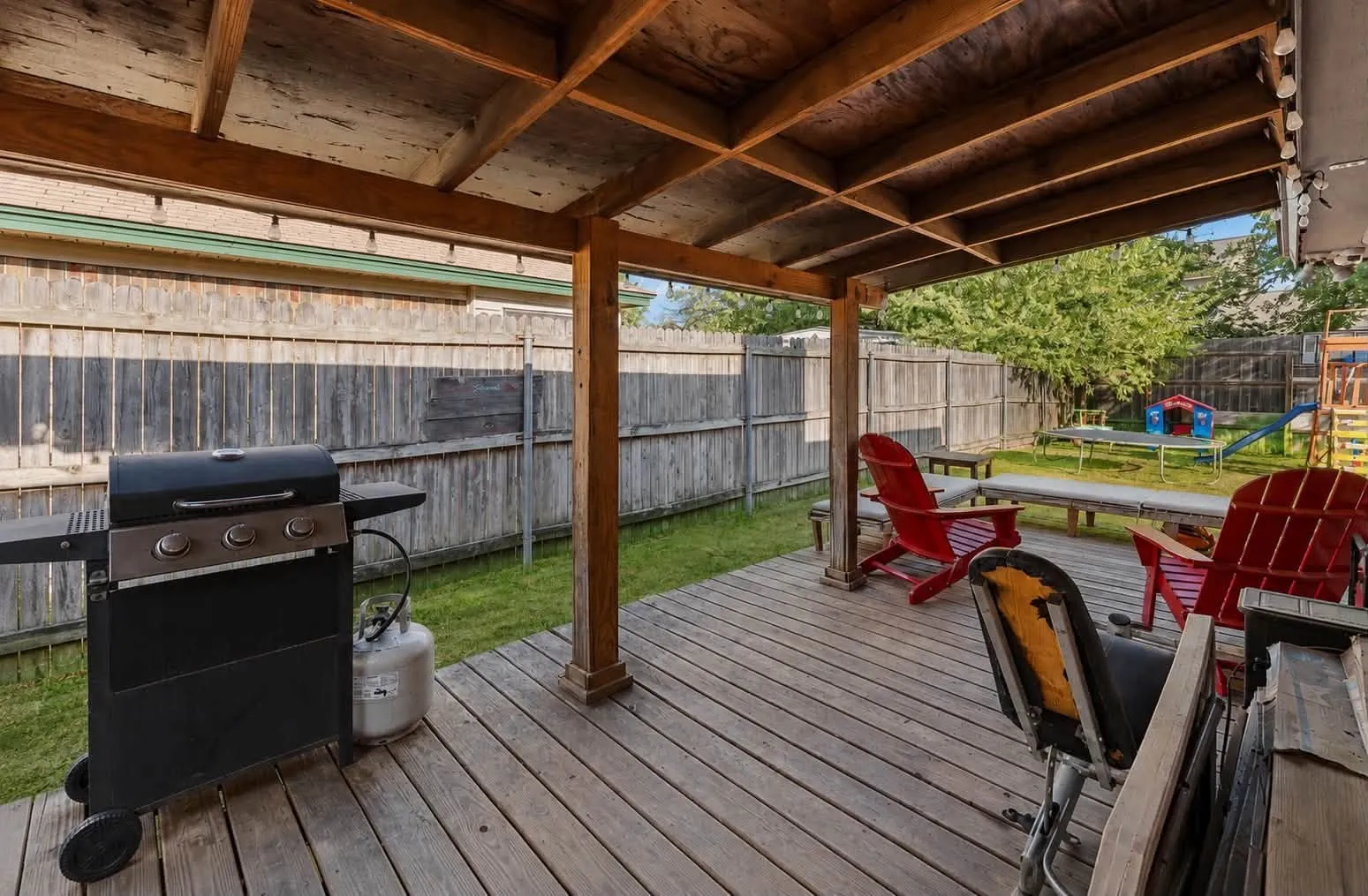 Wood deck with a covered patio, wood beam ceiling, and a fenced backyard with mature trees