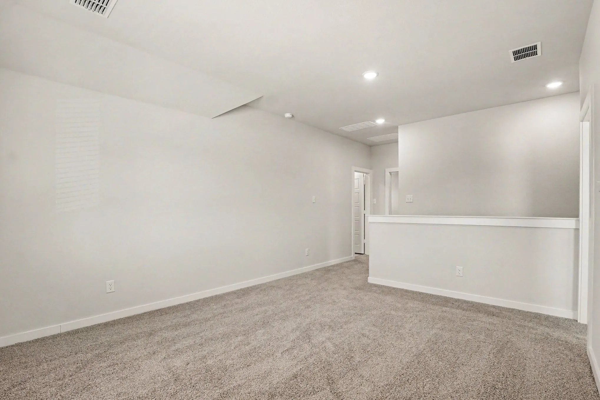 Carpeted room with recessed lighting, white walls, and a half-wall partition