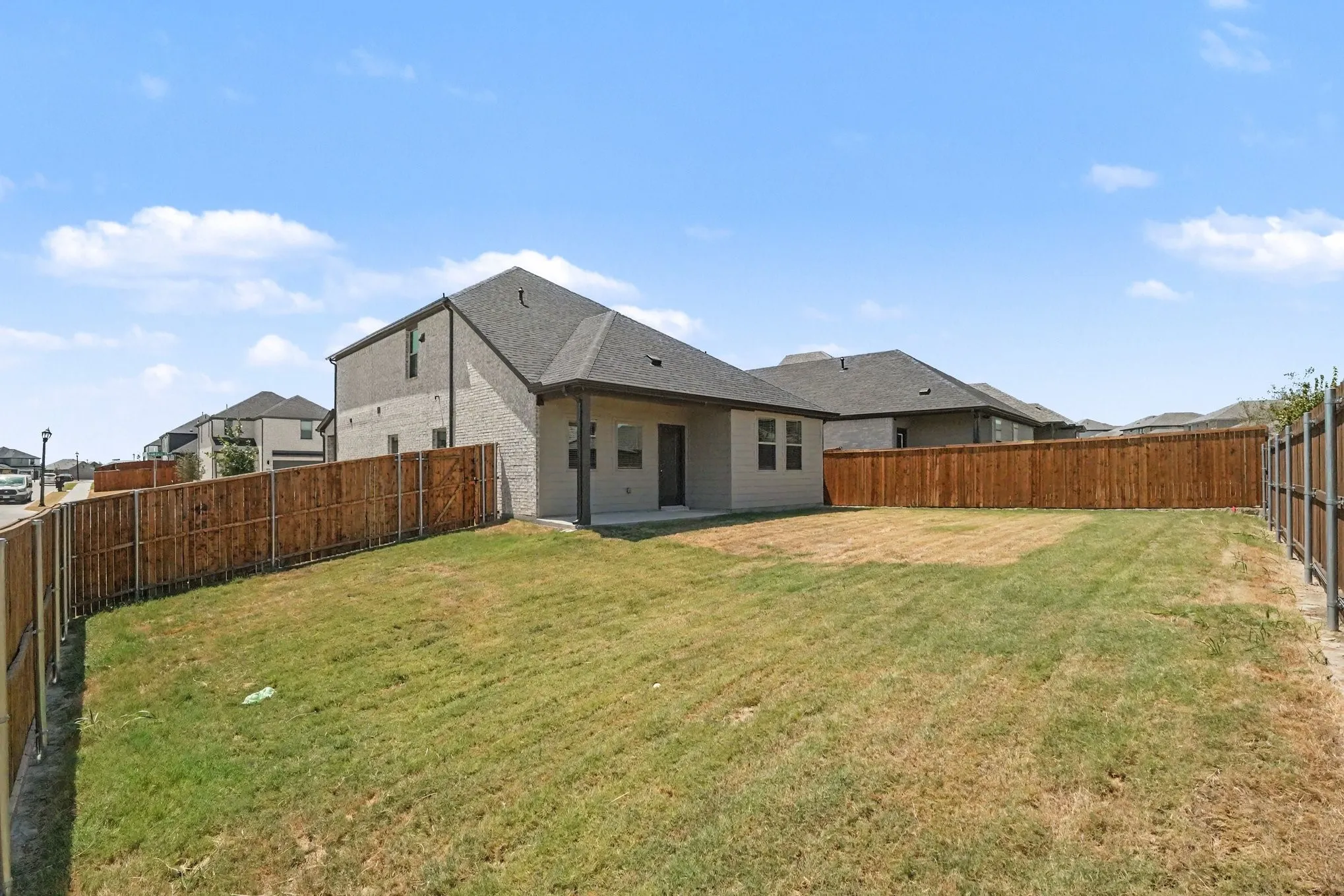 Expansive backyard space with a privacy fence and a covered patio area