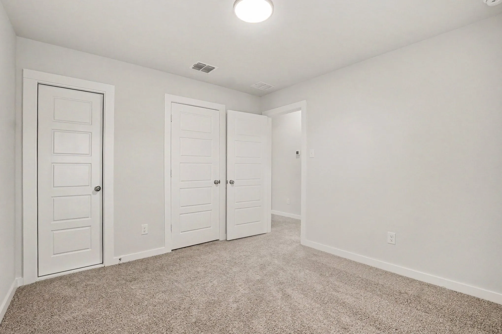 Neutral wall tones, carpeted flooring, and a flush mount ceiling light