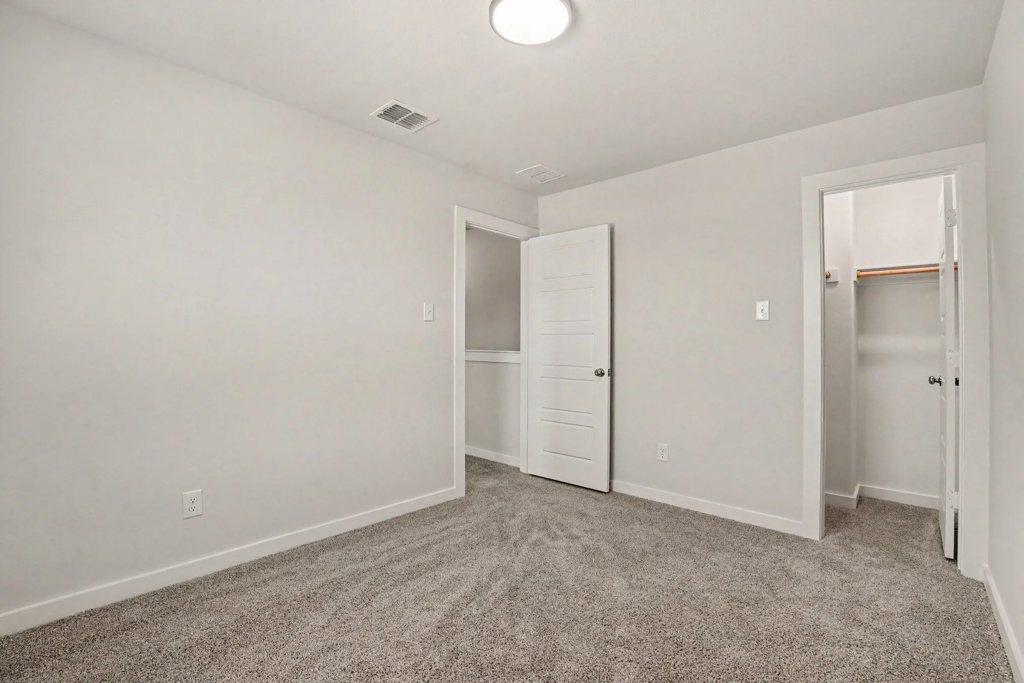 Carpeted flooring, white interior doors, and a built-in closet with shelving and a hanging rod