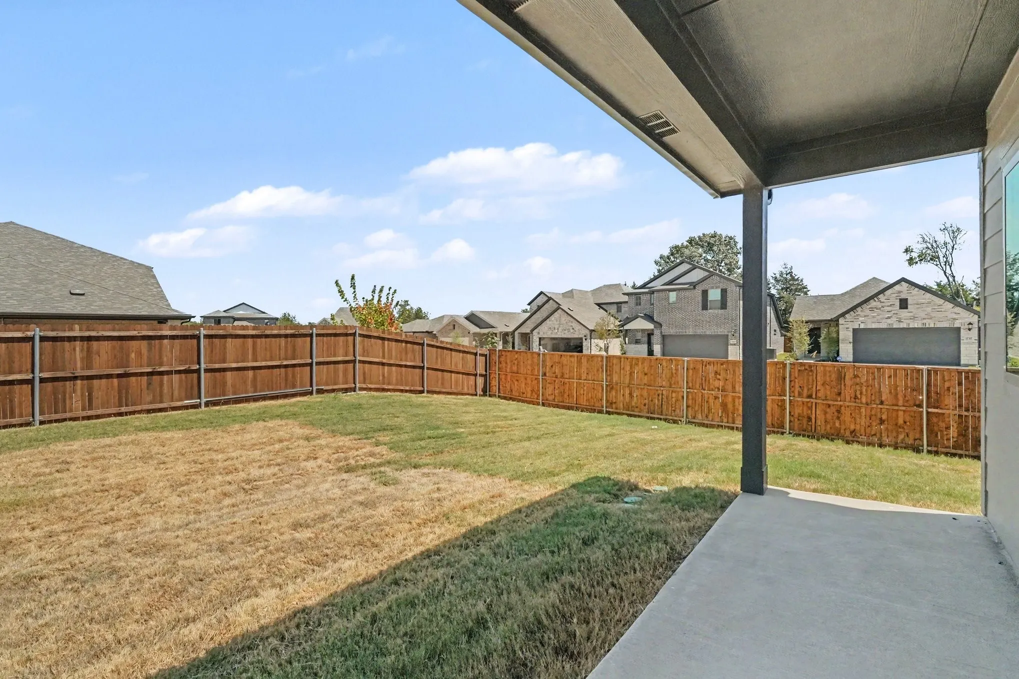 Expansive backyard fence, concrete patio, and covered outdoor area