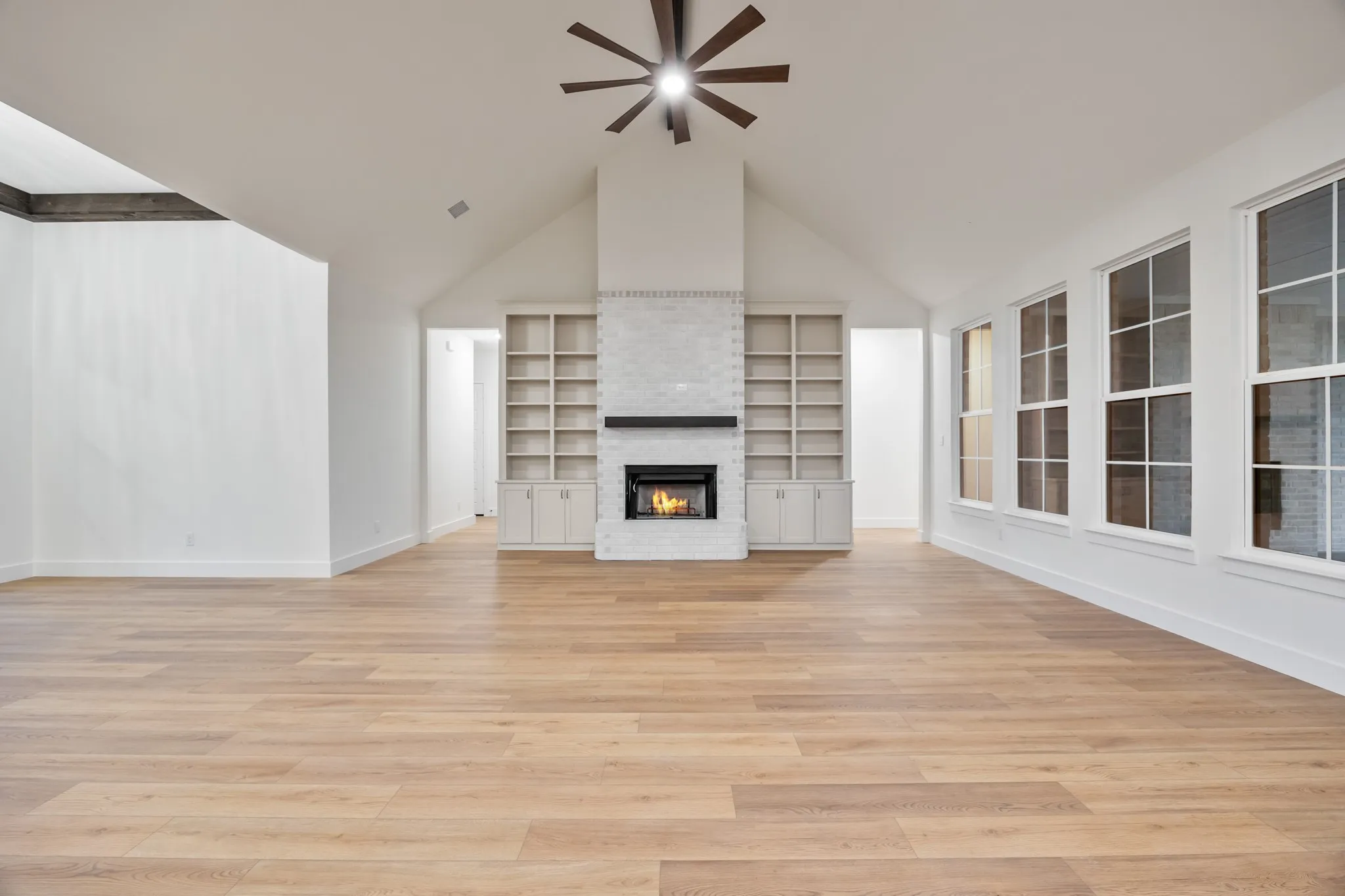 featuring high vaulted ceiling, light wood finished floors, beam ceiling, a chandelier, and ceiling fan
