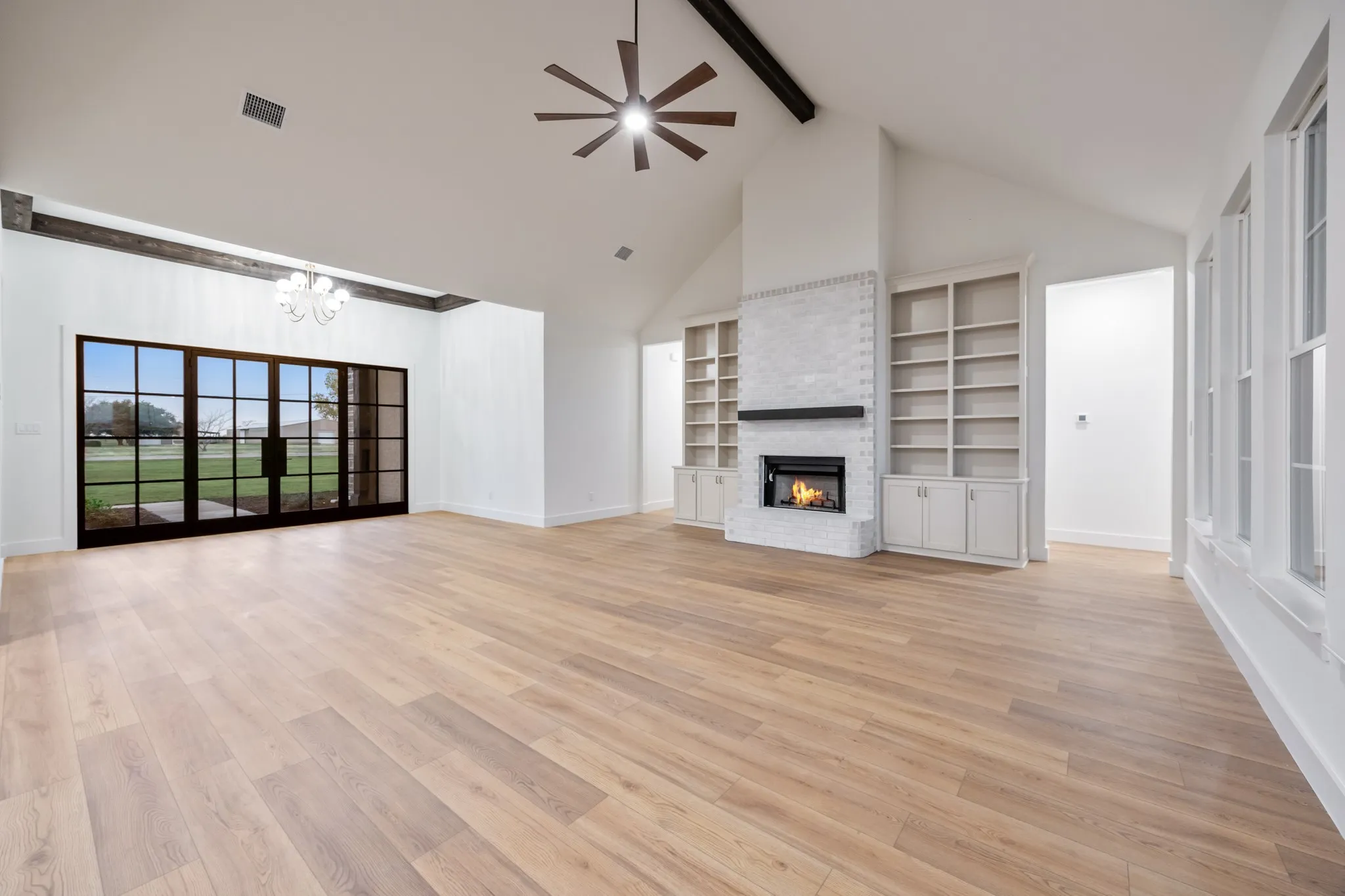 featuring high vaulted ceiling, light wood finished floors, beam ceiling, a chandelier, and ceiling fan