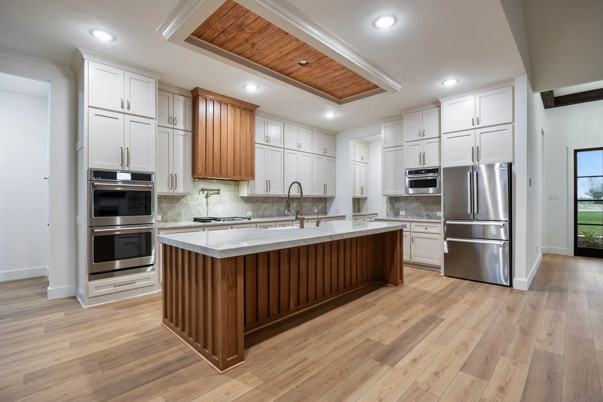 Kitchen featuring white Cabinets, light Wood-Type Floors, Island with sink and decorative hardware in an Open Floor Plan!