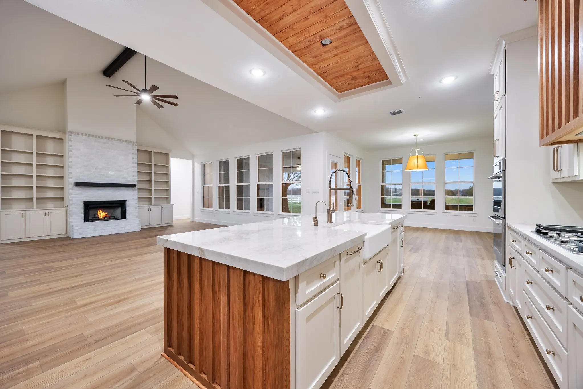 Unfurnished living room featuring high vaulted ceiling, light wood finished floors, beam ceiling, a chandelier, and ceiling fan