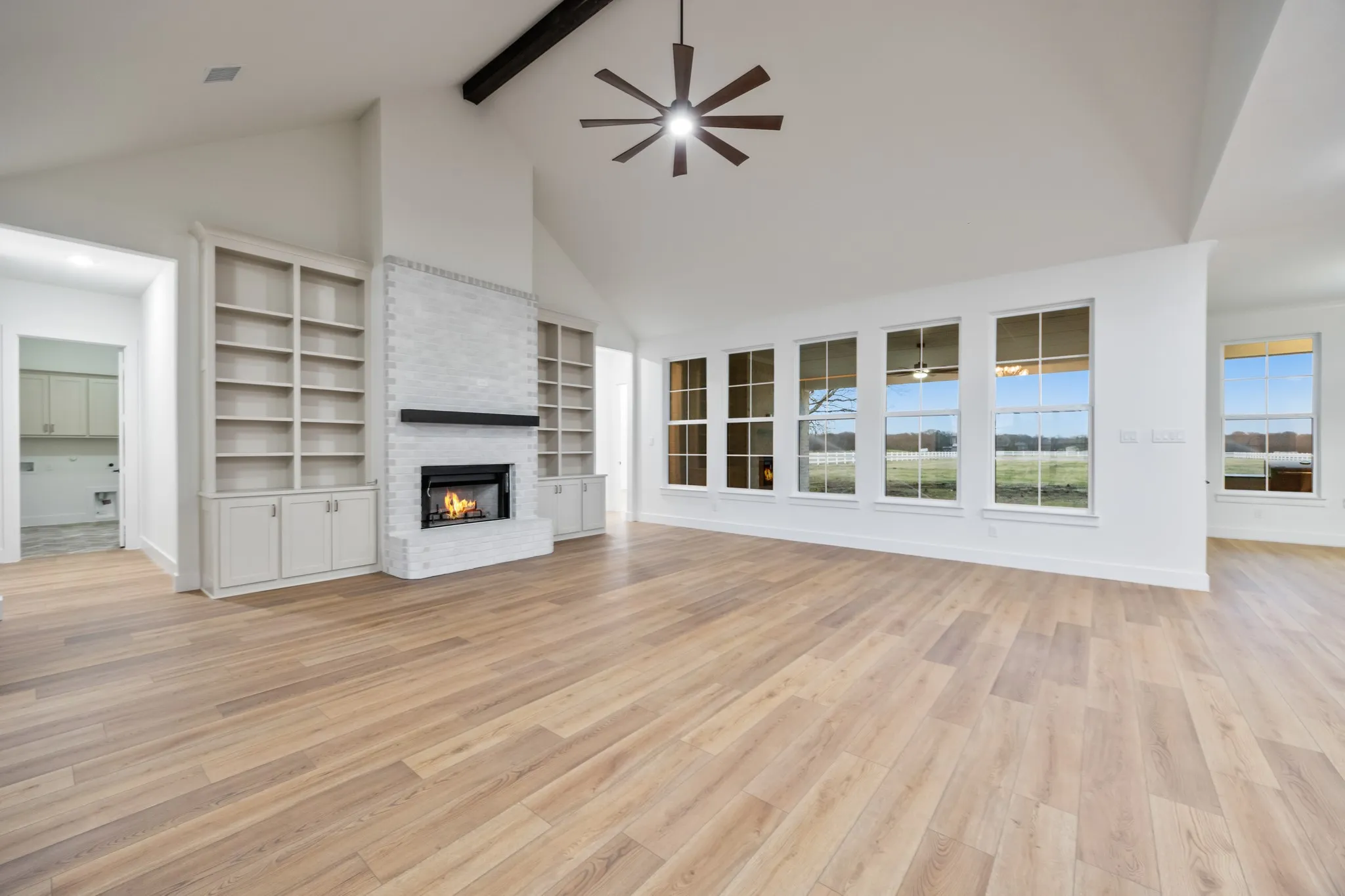 Living Room featuring high Vaulted Ceilings, Brick Fireplace, light Wood-type Floors, and built ins & ceiling Fans!