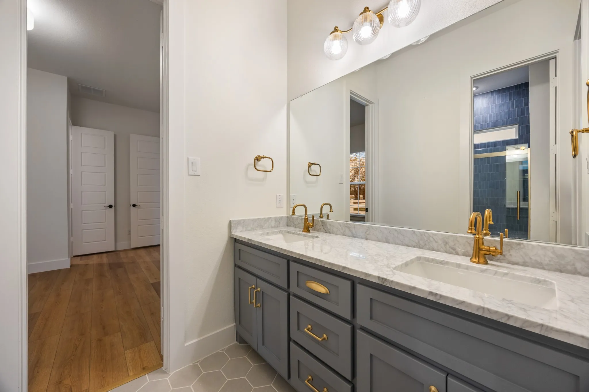 BATH with double sinks, gold fixtures plus decorative tiled flooring!