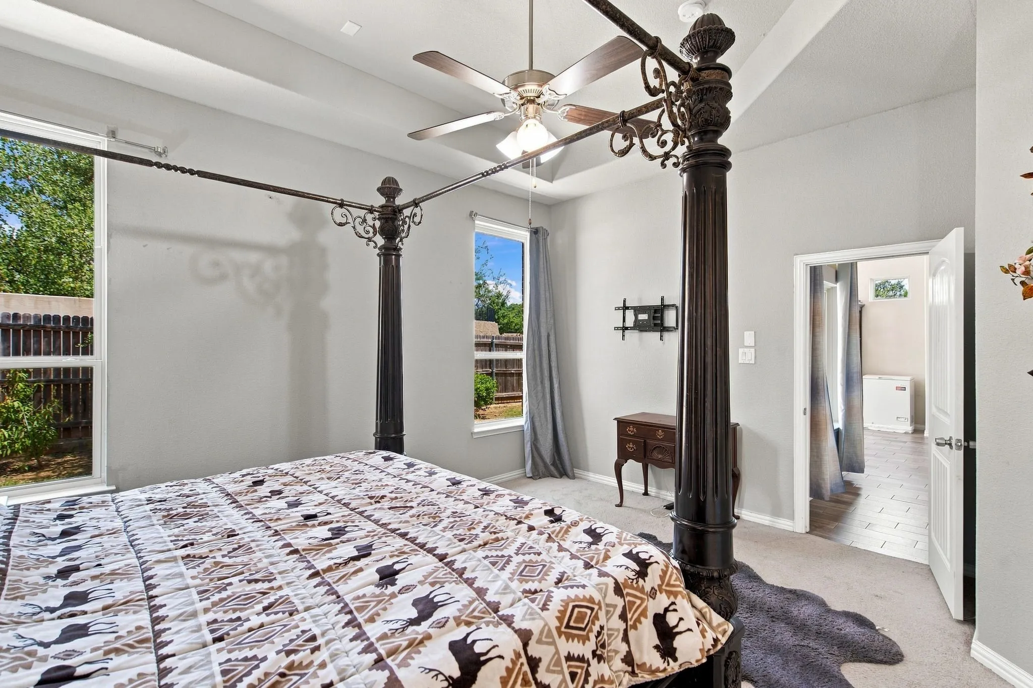 Tray ceiling with a ceiling fan, two large windows, and light gray wall paint