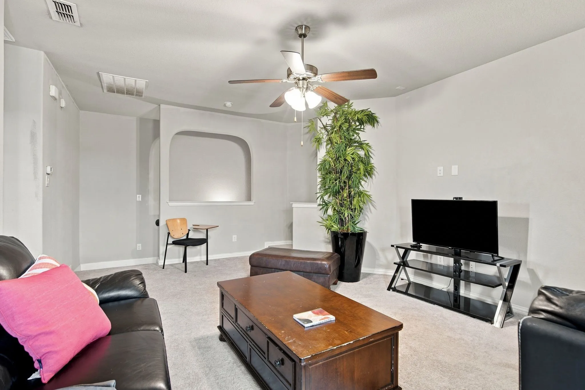 Recessed wall niche, ceiling fan with integrated lighting, and neutral carpeting