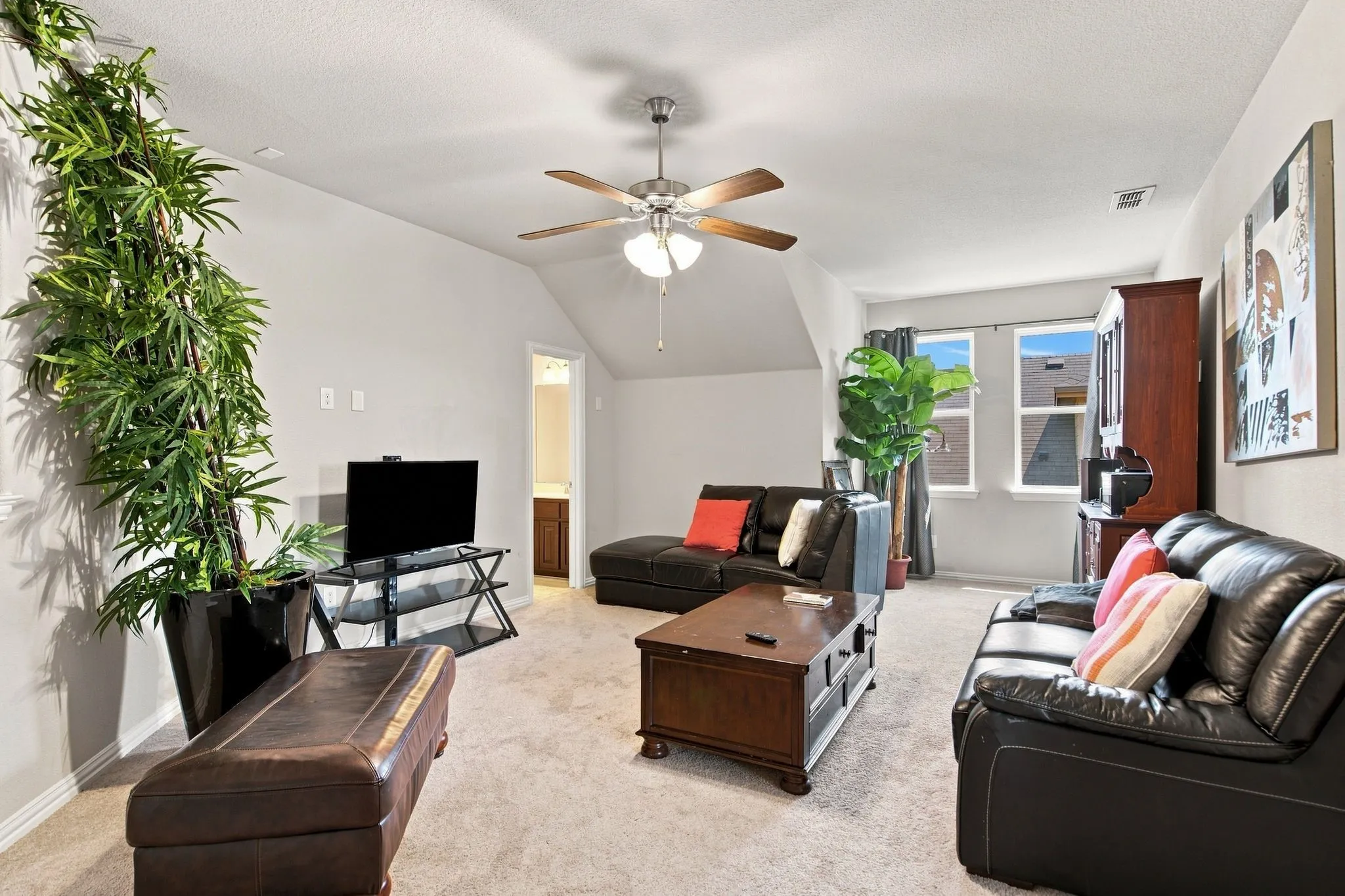 Game room upstairs featuring a ceiling fan with light fixture, light-colored carpet, and double windows