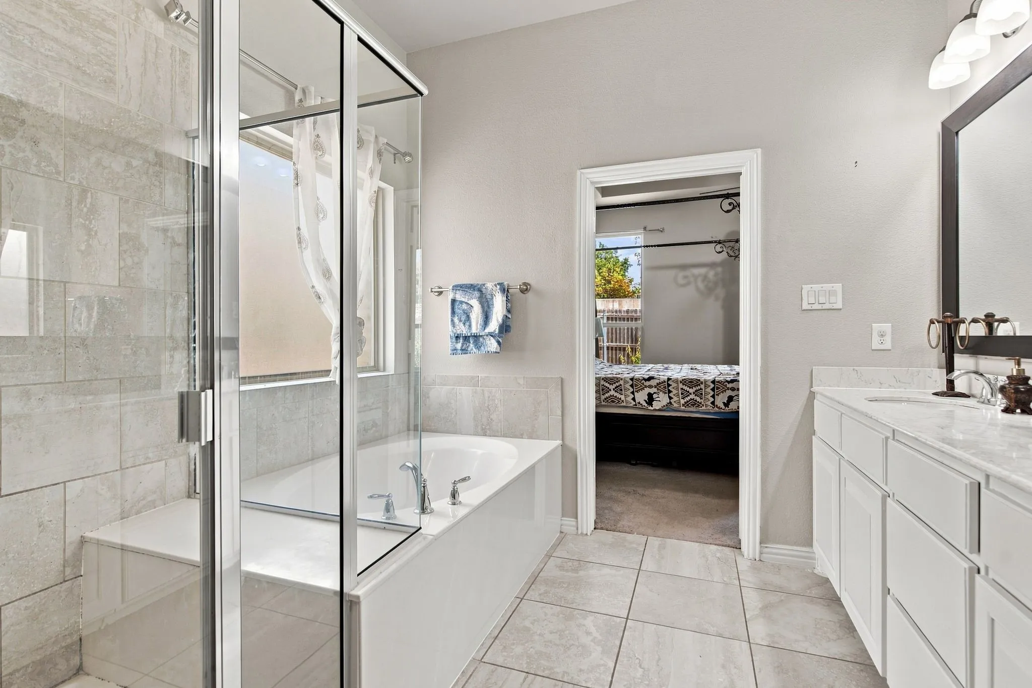 Shower enclosure with clear glass paneling, a built-in bench, and a tiled surround
