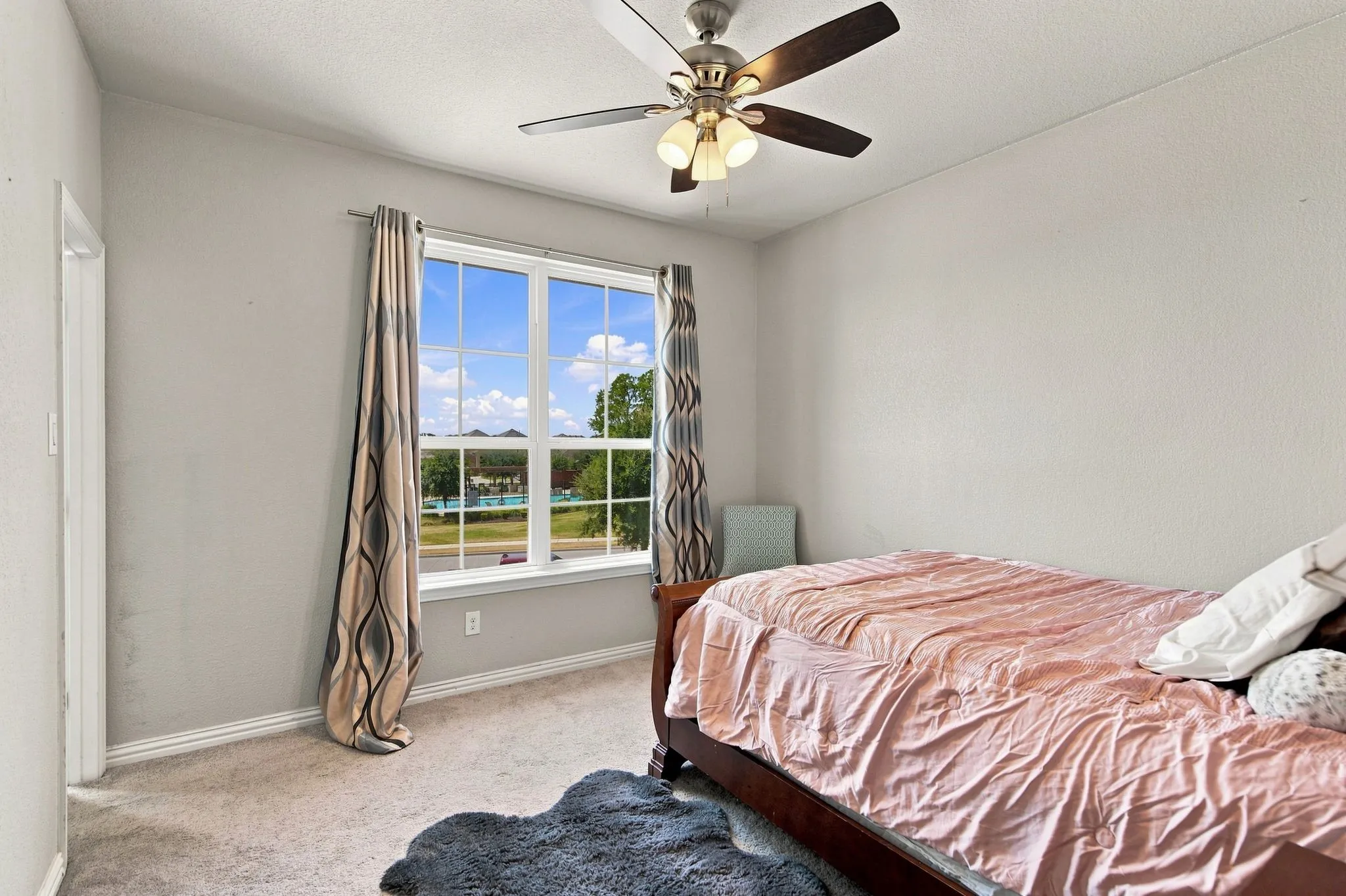 Plush carpeting, a multi-pane window, and a ceiling fan with integrated lighting